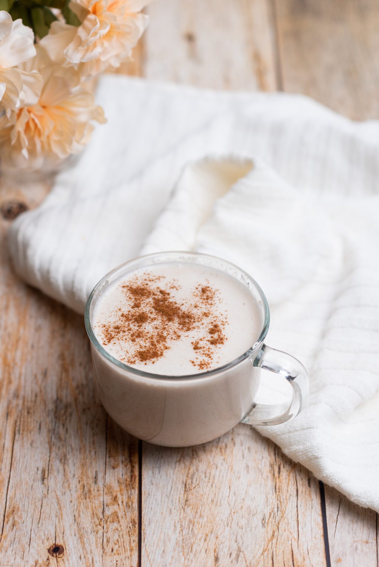 A glass of eggnog with cinnamon on a wooden table.