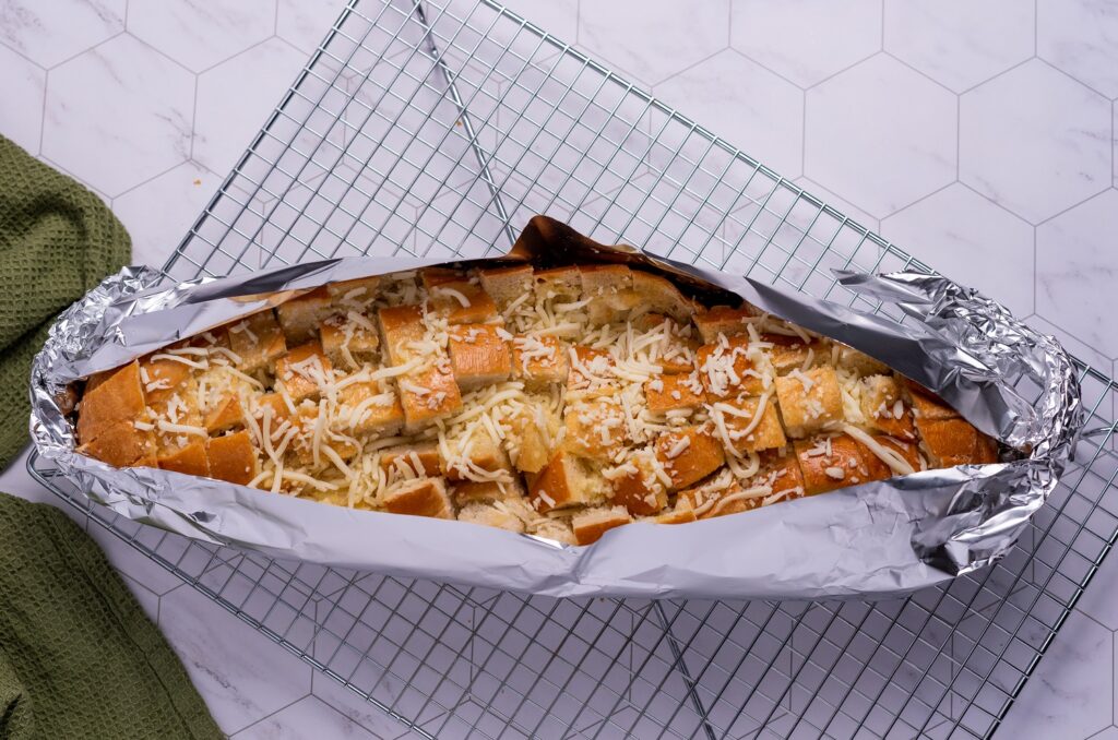 Cheesy Garlic Pull Apart Bread sits in tin foil, ready to be baked in the oven.