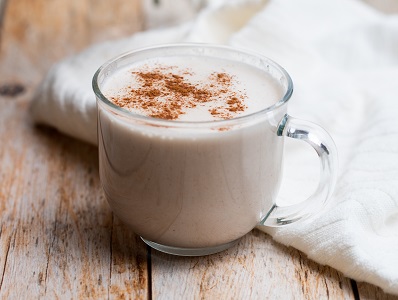 A Coconut Bourbon Eggnog in a glass with spice sprinkled on top.