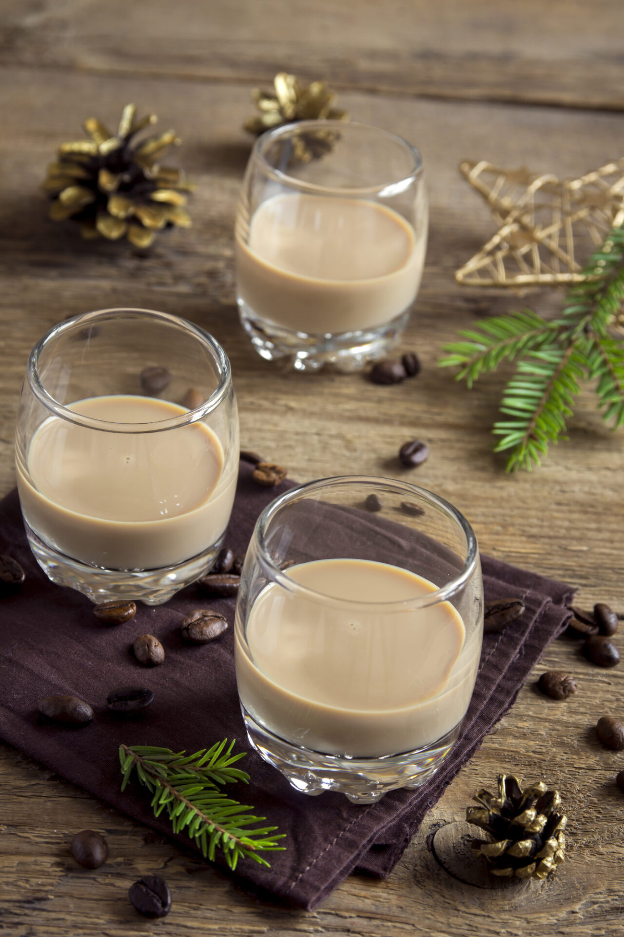 Glasses of homemade Baileys on a wooden counter.