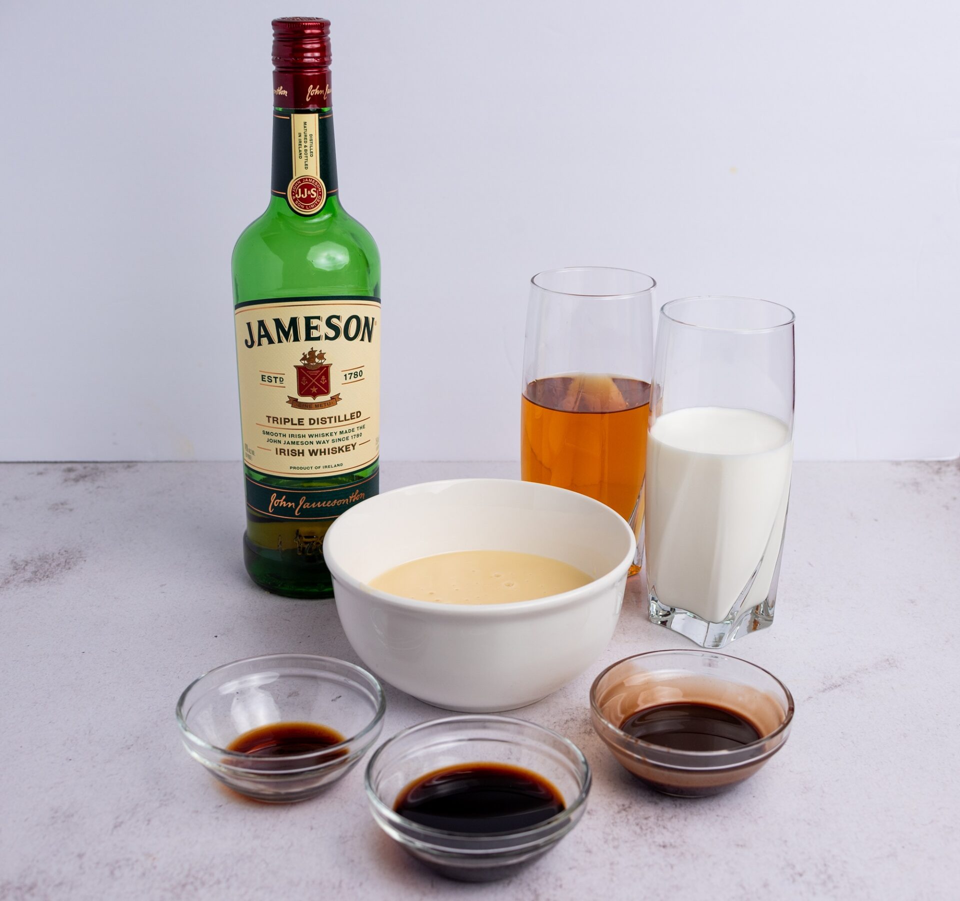 Ingredients for homemade Baileys on a white counter.