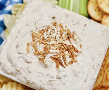 French Onion dip appetizer on a platter surrounded with carrots, celery and crackers.