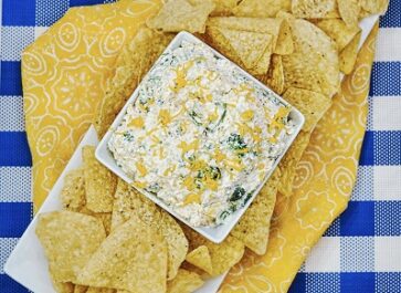 Broccoli cheese dip in a bowl beside tortilla chips