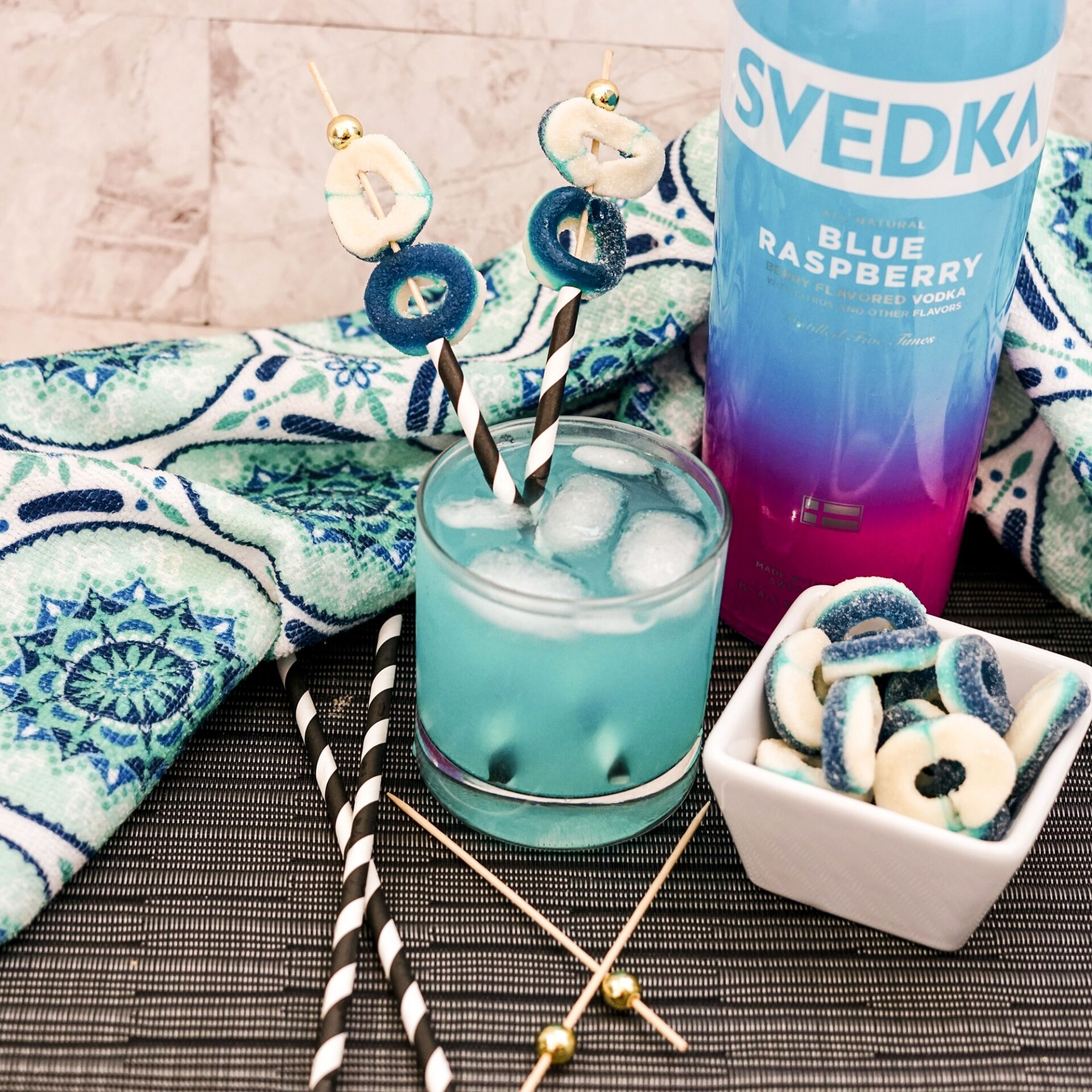 Blue raspberry vodka cocktail on a counter with ingredients.