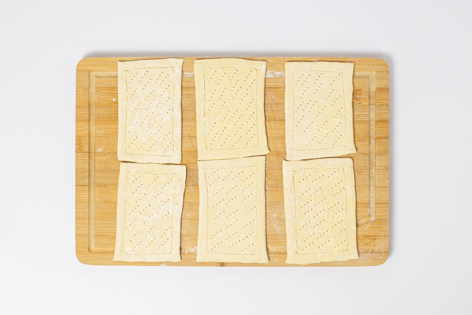 Scored puff pastry on a cutting board.