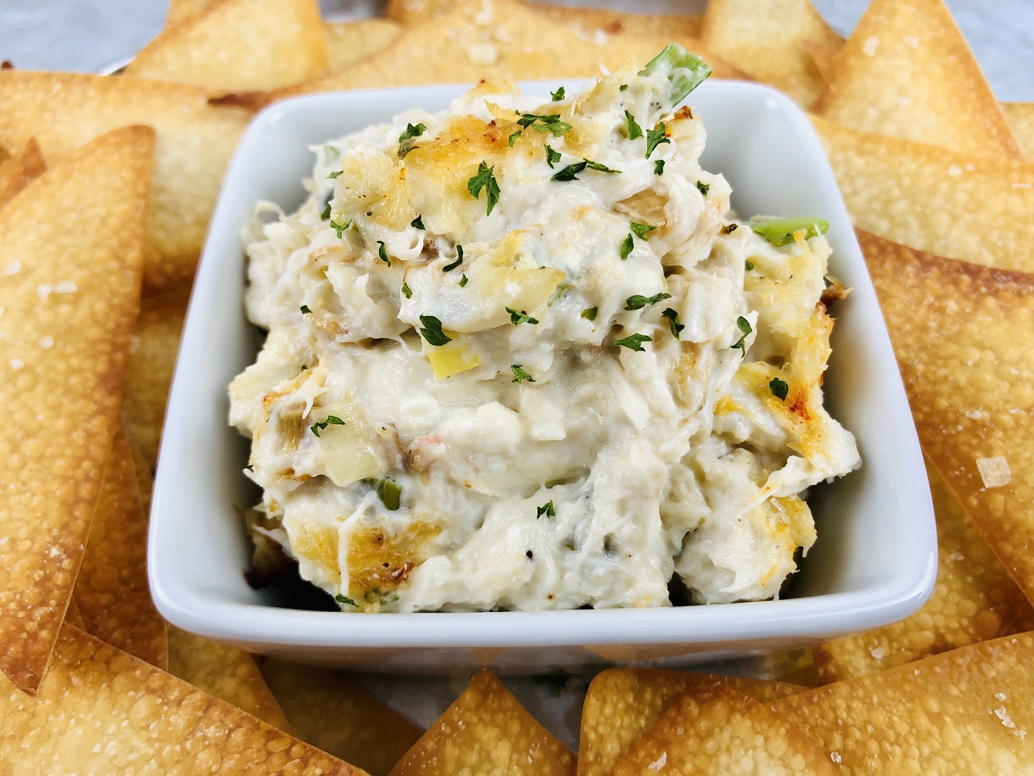 crab rangoon dip in a bowl surrounded by wonton chips