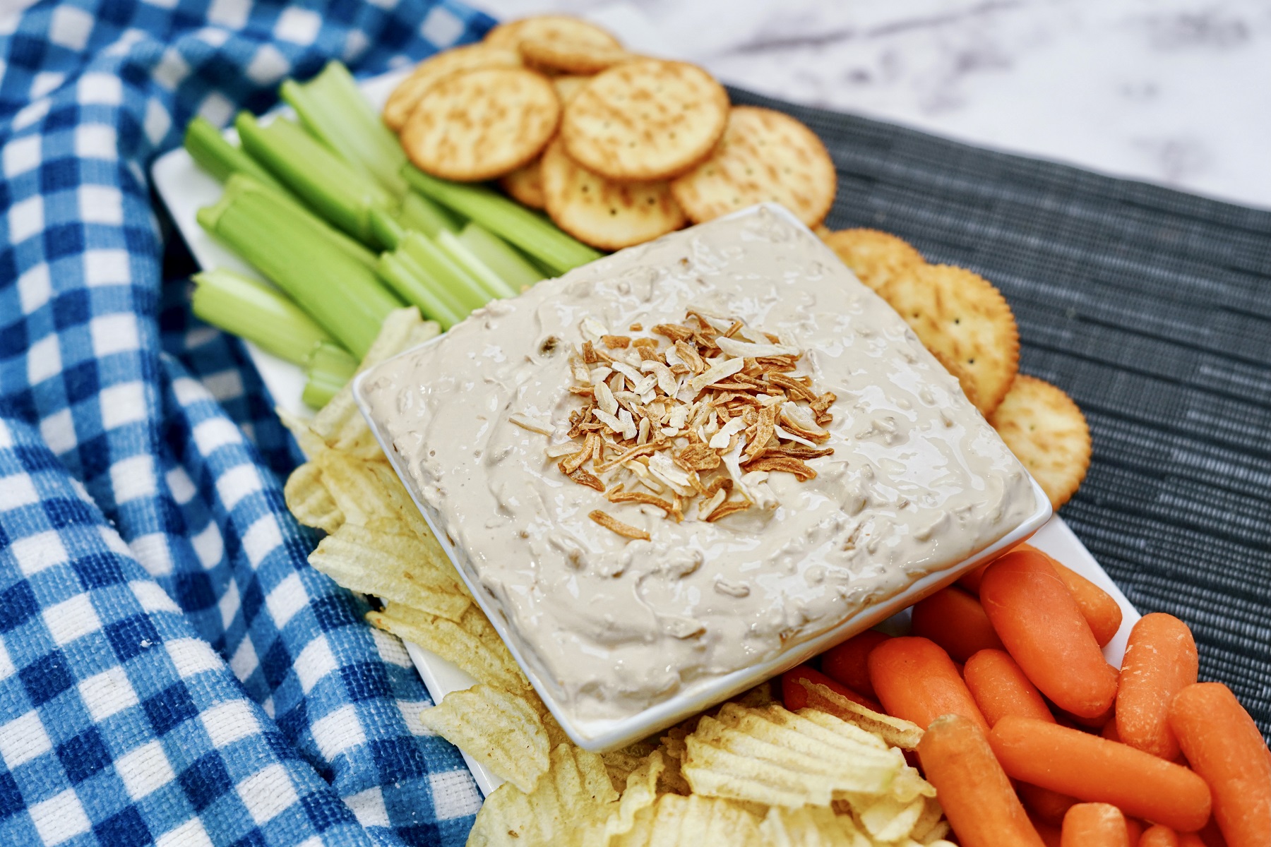 french onion dip in a bowl surroudning by crackers, chips, and veggies