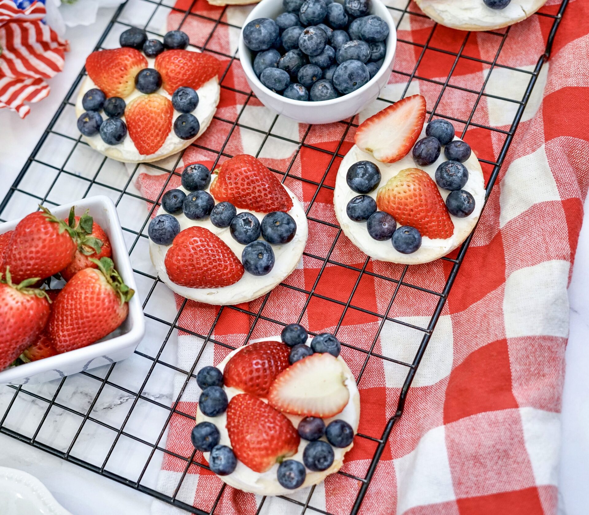 mini fruit pizzas on a wire rack above a checkered red tablecloth.