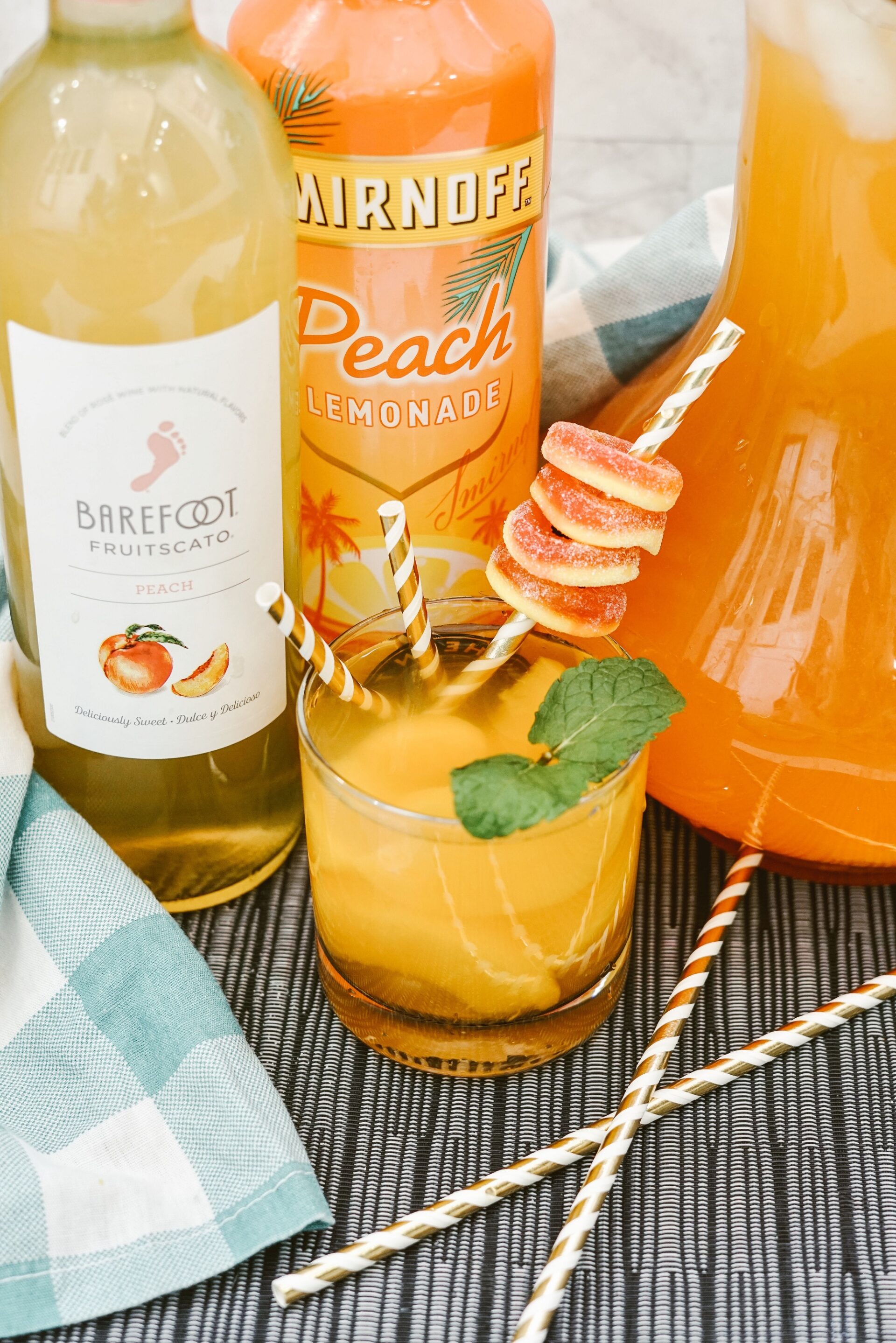 peach sangria in a glass next to pitcher and ingredients.