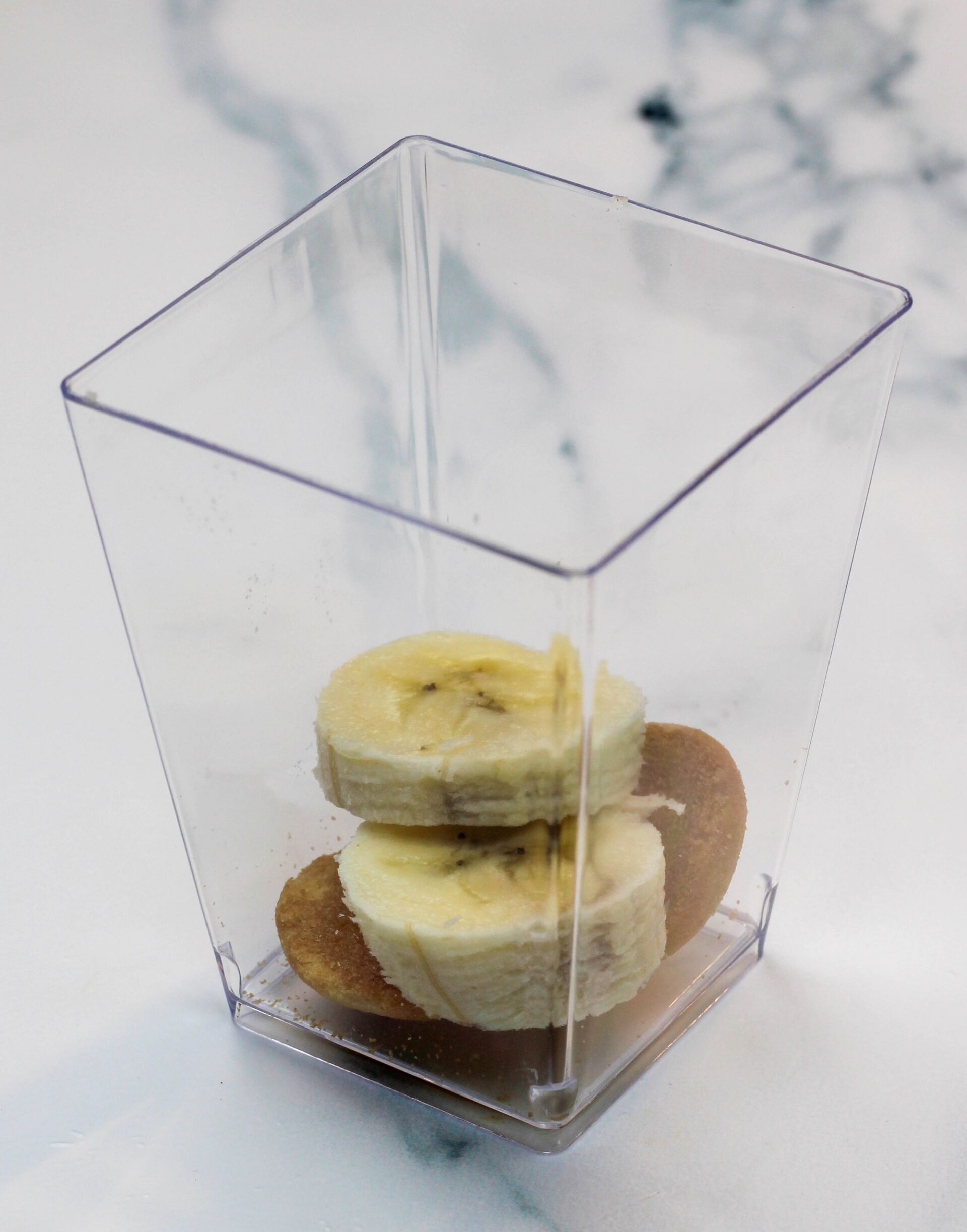 Banana slices and nilla wafers in a rectangular cup.
