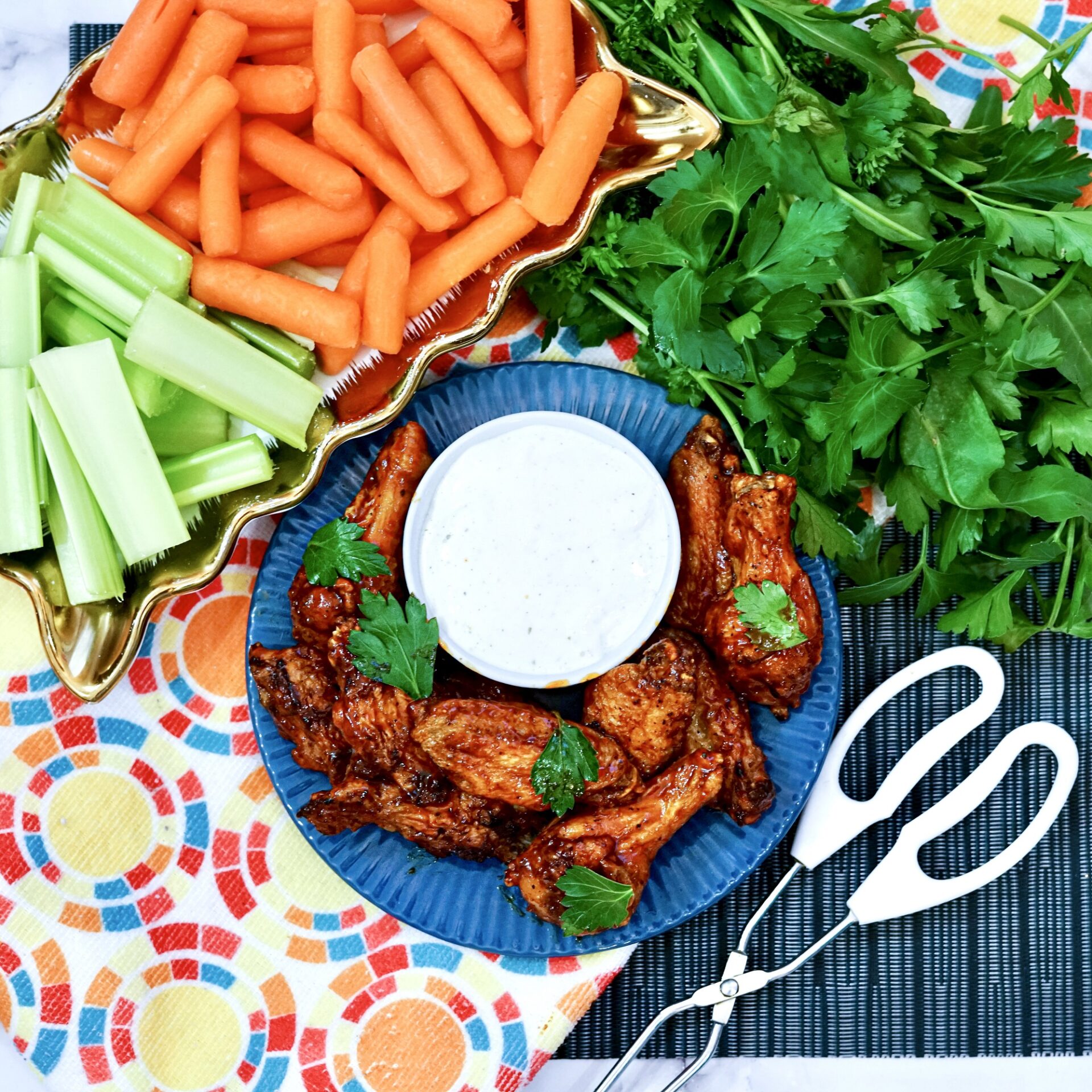 air fryer bbq chicken wings on a plate with dressing and vegetables.