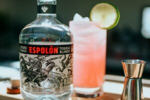 Espolòn Blanco Tequila bottle with pink tequila cocktail