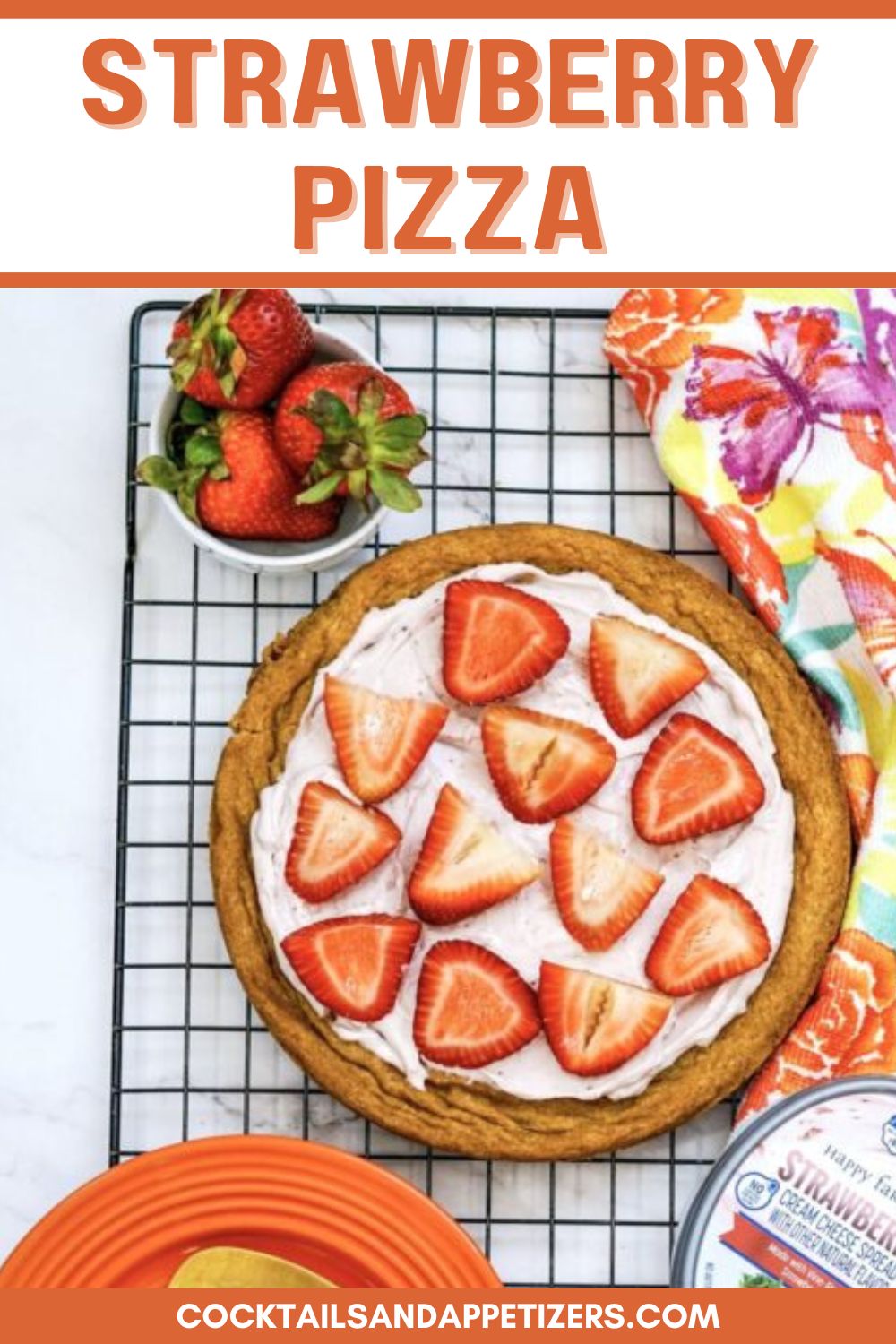 Strawberry pizza sitting on a cooling rack, with a bowl of strawberries beside.