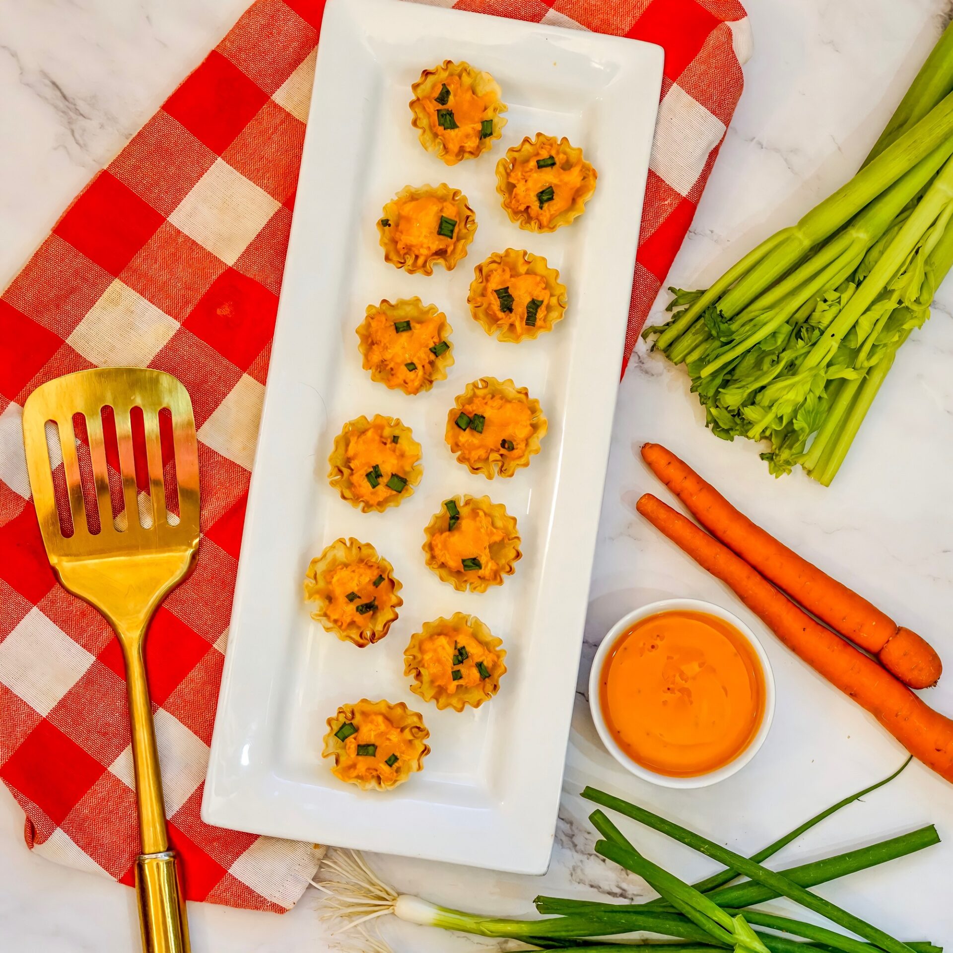 Buffalo chicken cups on a platter with sauce and veggies.