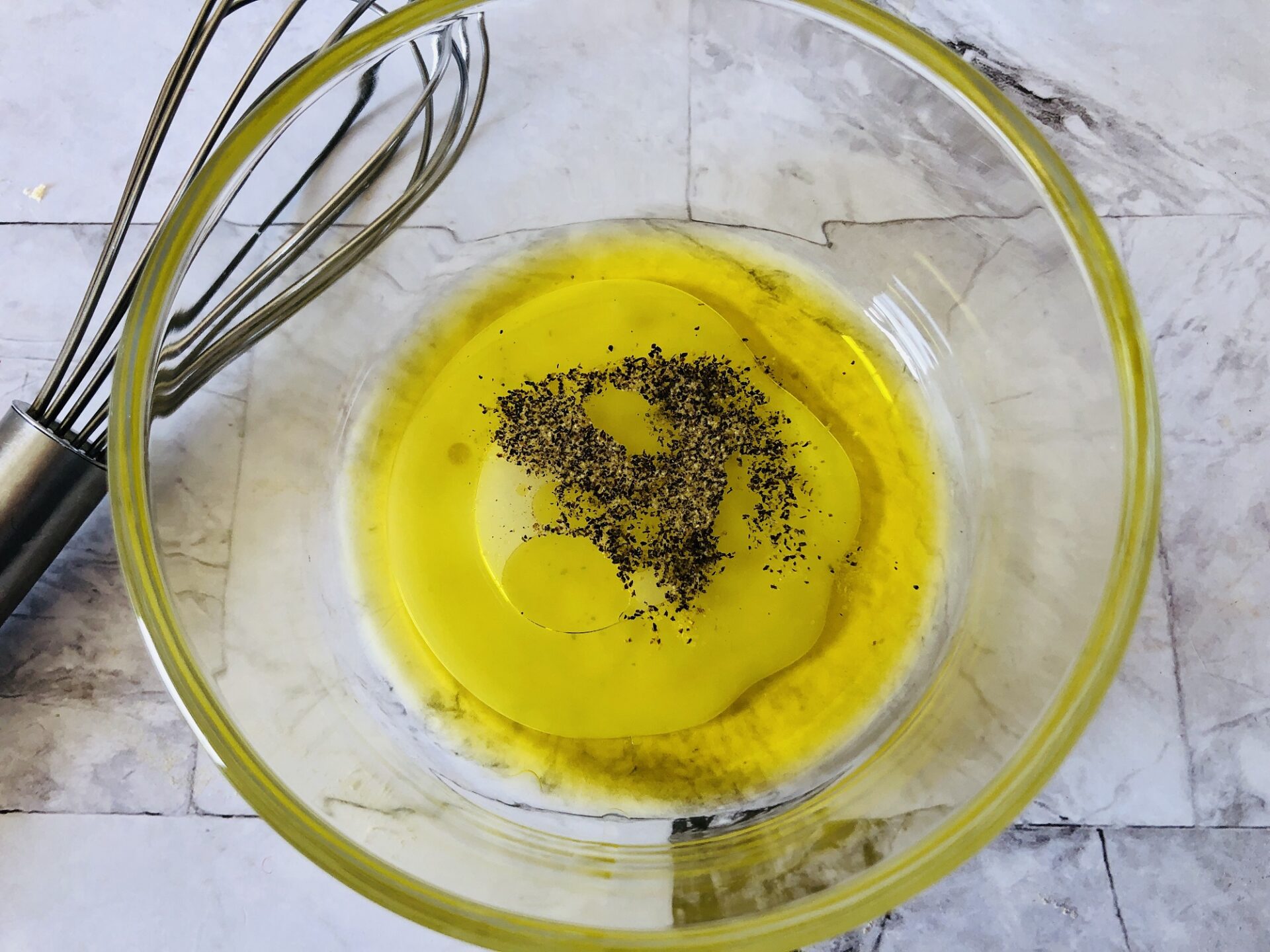 Mixing lemon vinaigrette in a glass bowl.