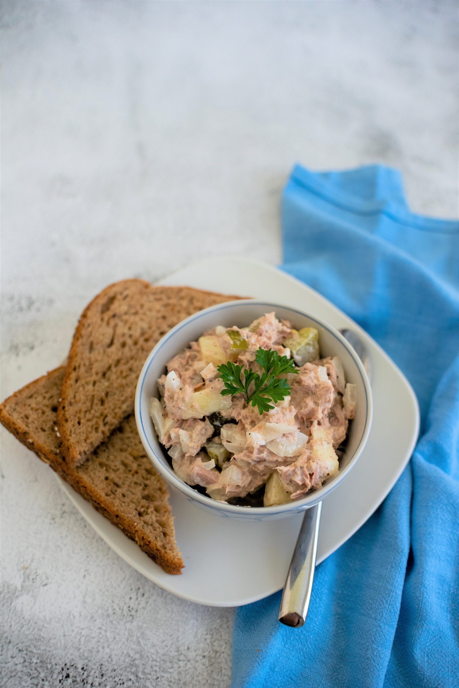 A bowl of easy tuna salad on a plate with bread.