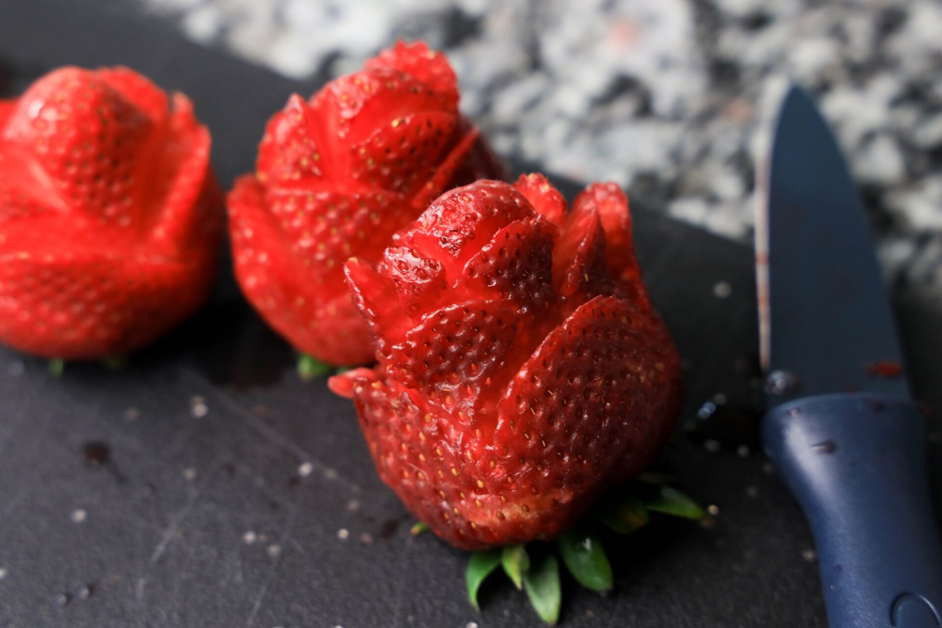 Cutting a strawberry into a rose shape.