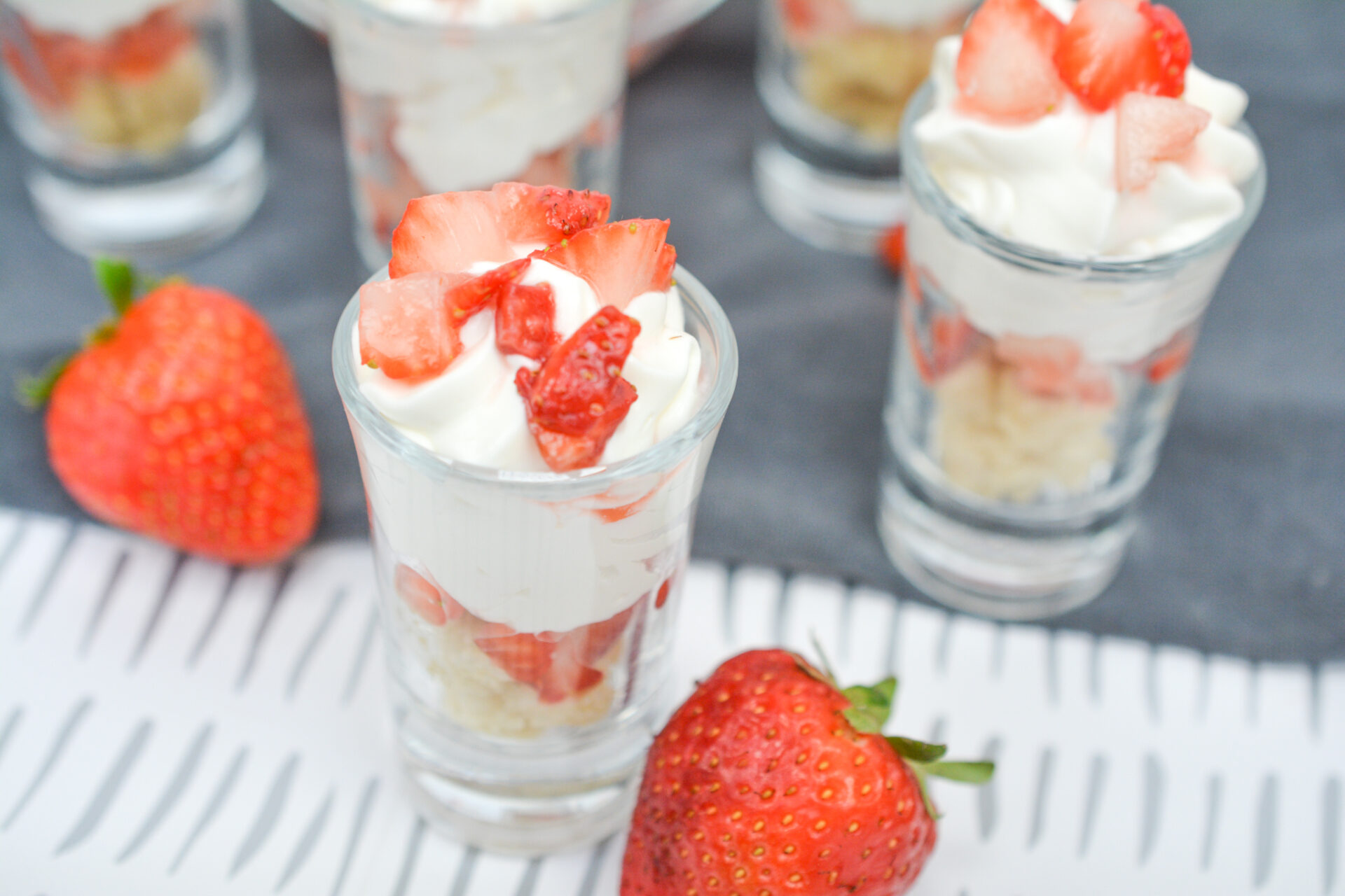 Strawberry Shortcake Shooters on a counter with strawberries.