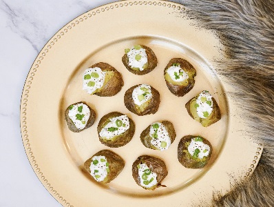 Air Fryer Mini potatoes with sour cream and chives sitting on a gold plate.