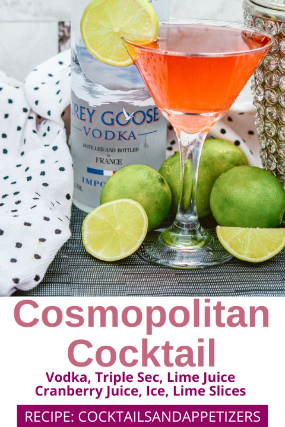 Cosmopolitan cocktail in a martini glass with limes and a vodka bottle.