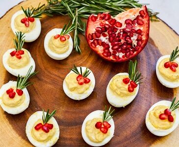 Deviled Eggs with pomegranate seed garnish on a wood slab