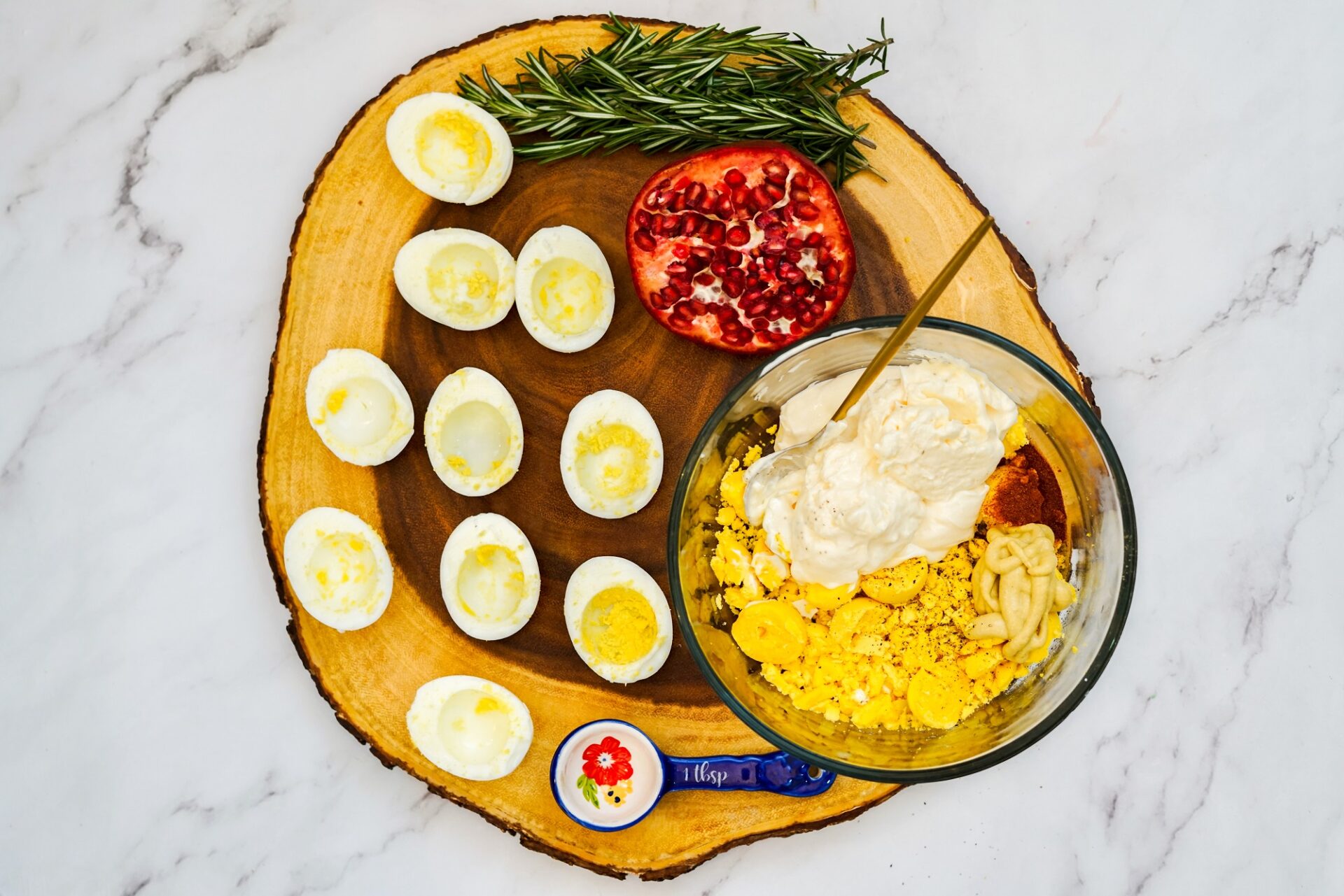 Empty egg whites arranged next to a bowl of deviled egg ingredients.