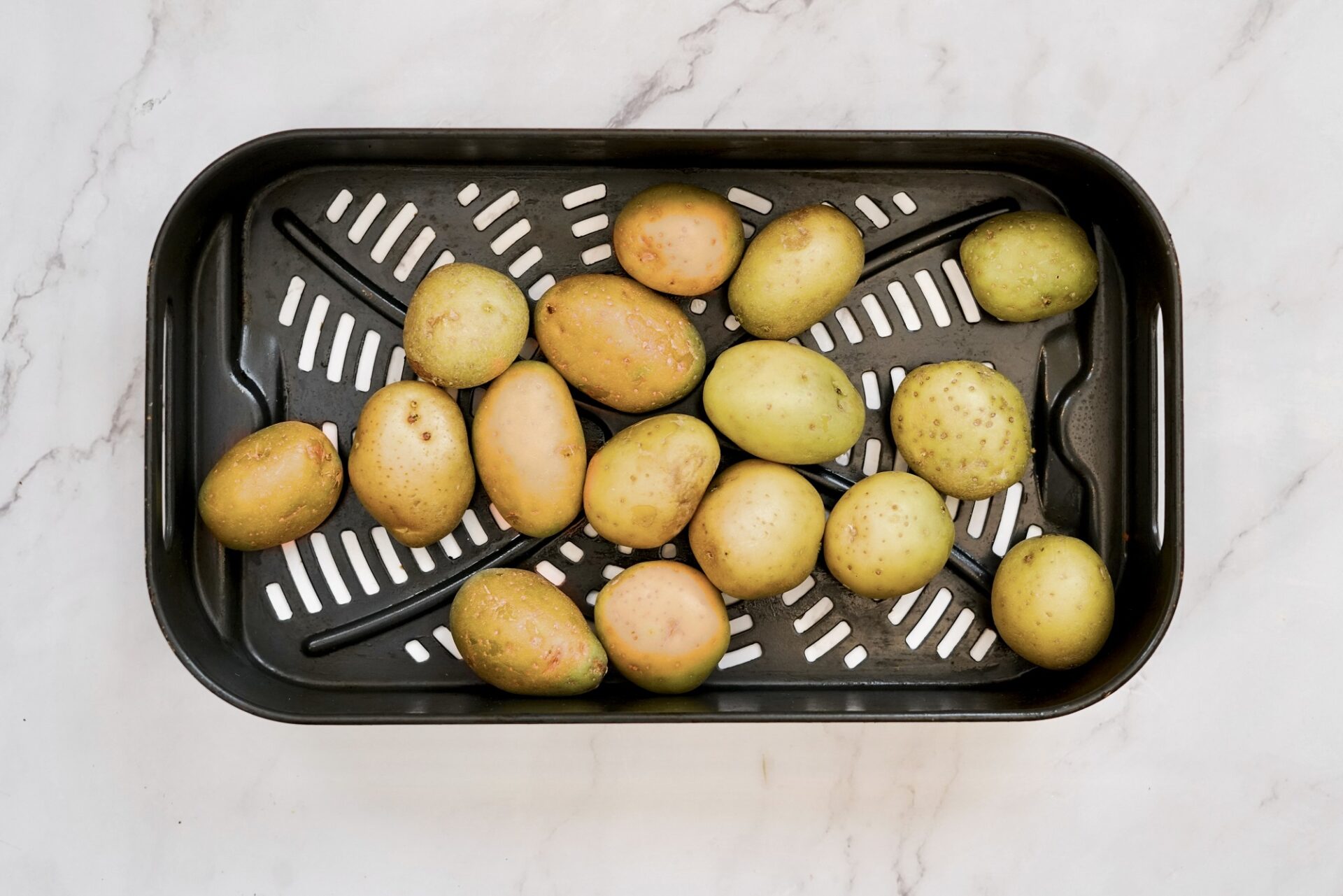Mini potatoes in the air fryer basket.