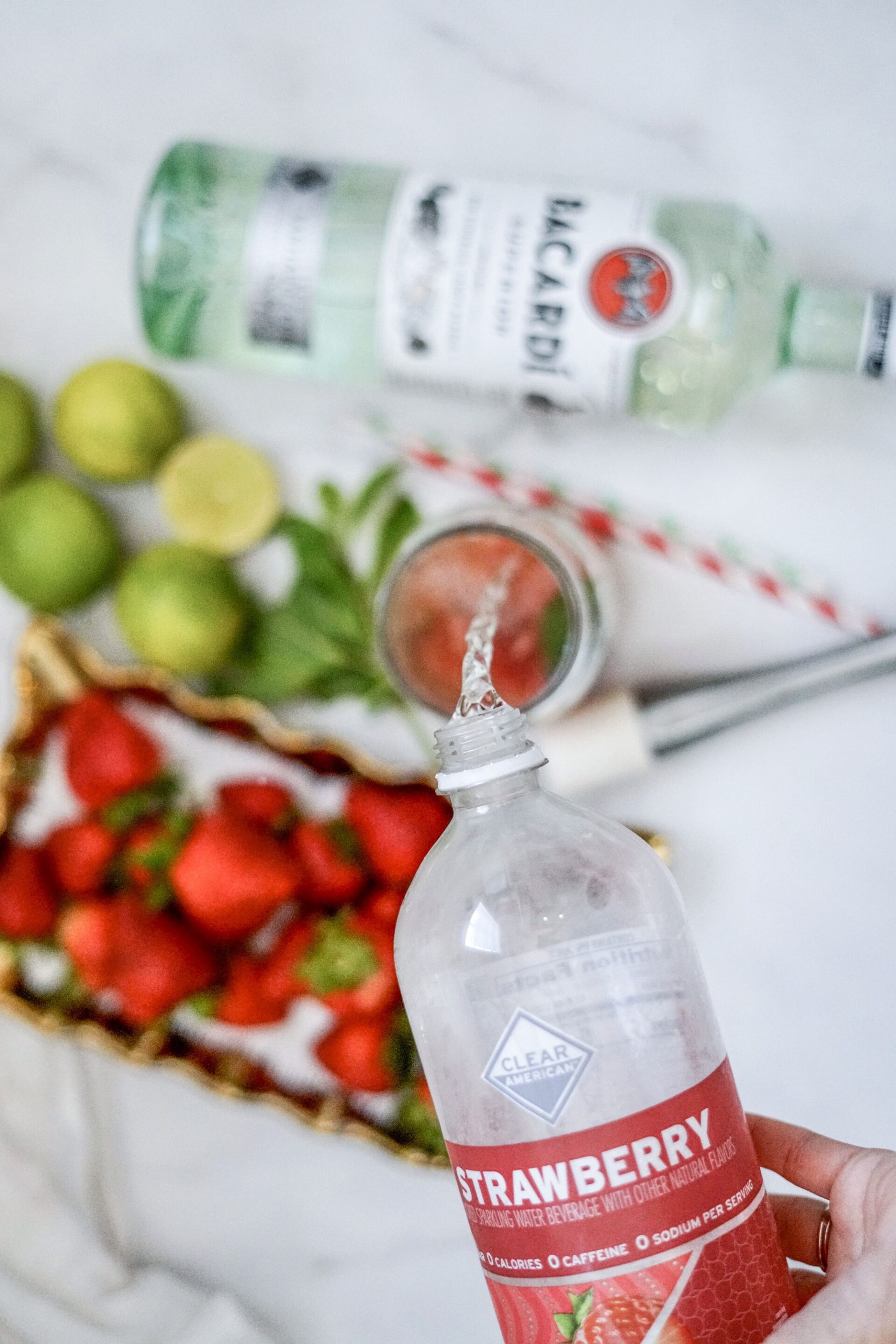 Pouring strawberry sparkling water into a glass.