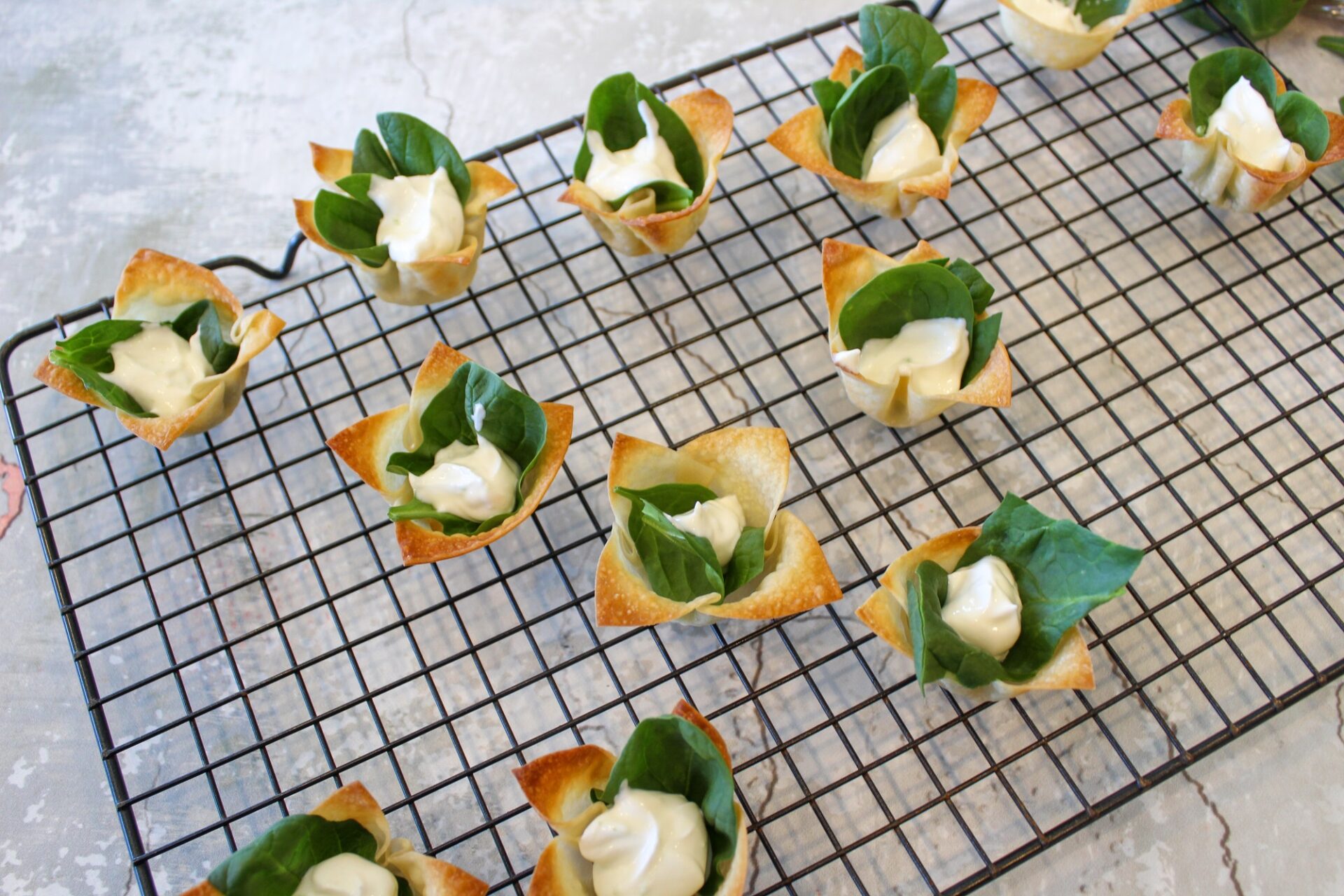 Wonton cups with sour cream sauce and spinach.