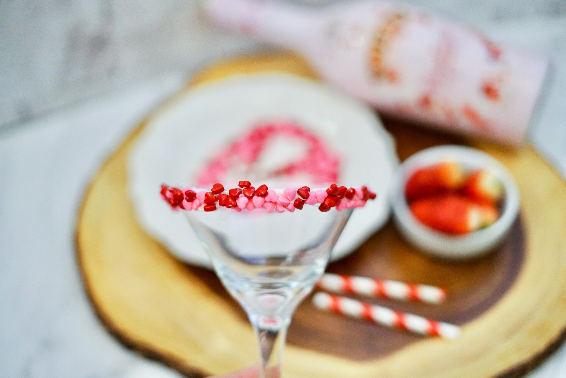 Rimming a martini glass with frosting and heart sprinkles.