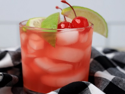 Bourbon Cherry Limeade drink in a highball glass with lime slice and cherry garnish.