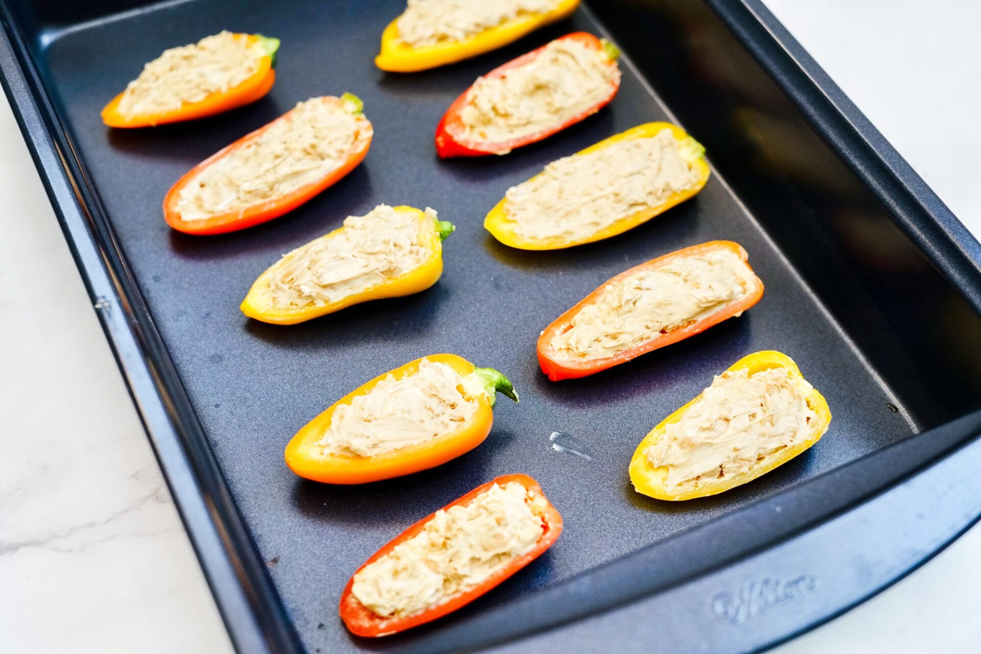 Unbaked stuffed peppers in a baking dish.