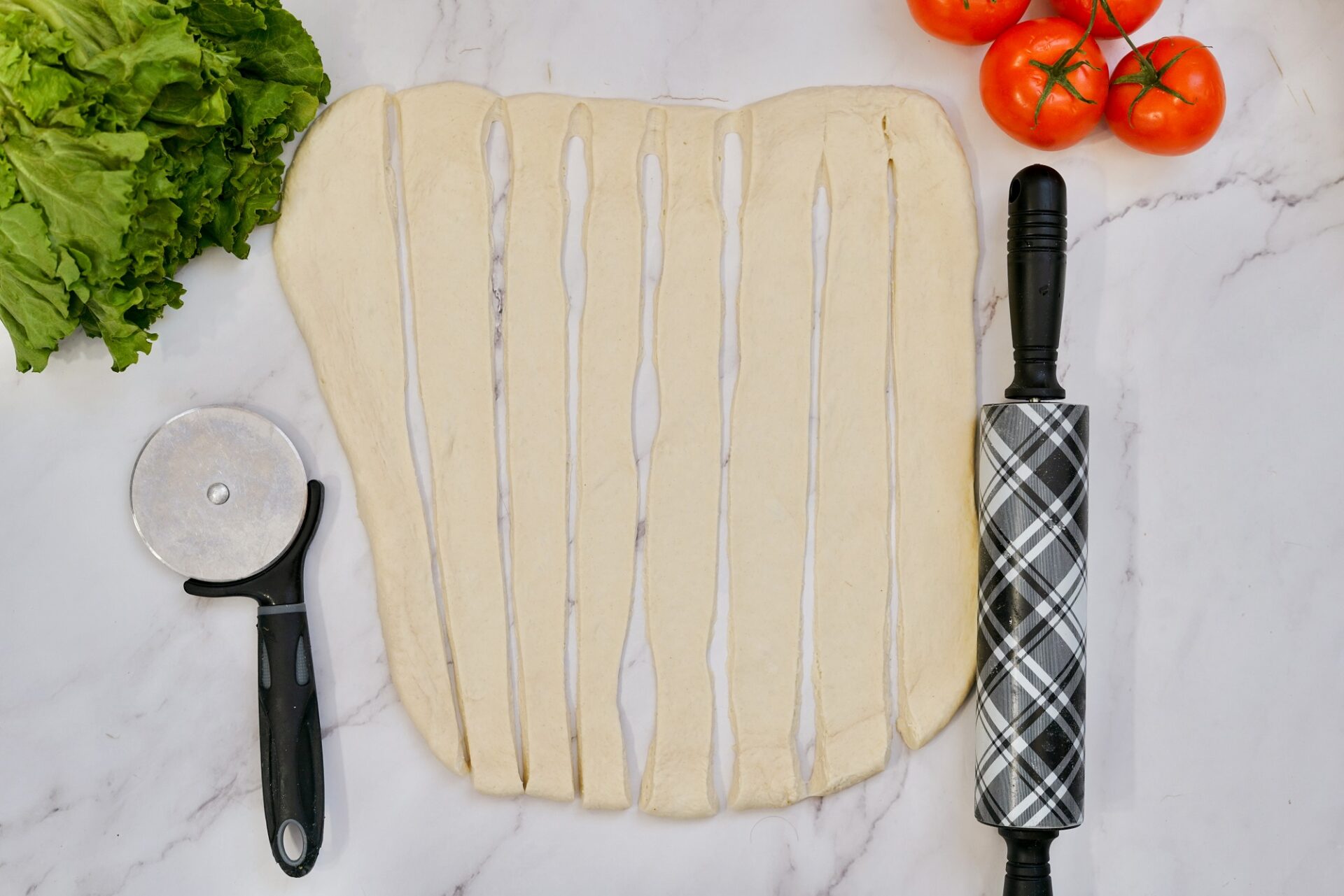 Cutting rolled out pizza dough into strips.