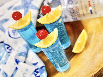 Blue Kamikaze shot in shot glass with cherry and lime garnish