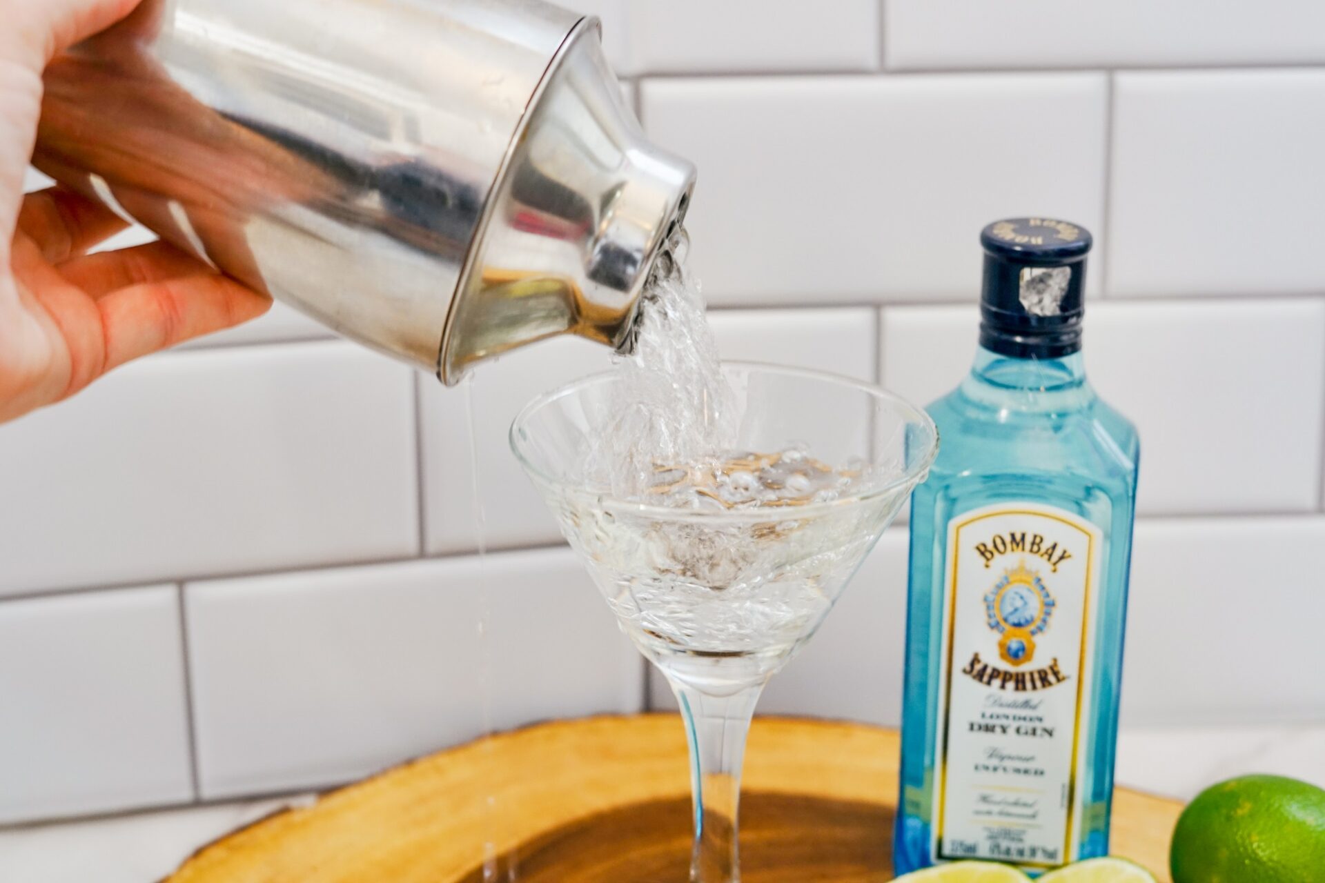 Pouring gin gimlet into a martini glass.