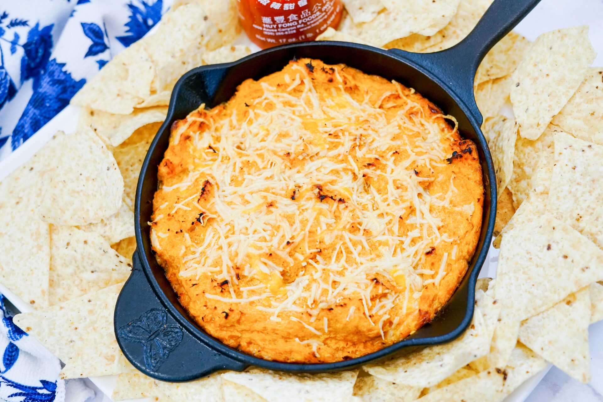 Honey sriracha chicken dip in a skillet surrounded by tortilla chips.