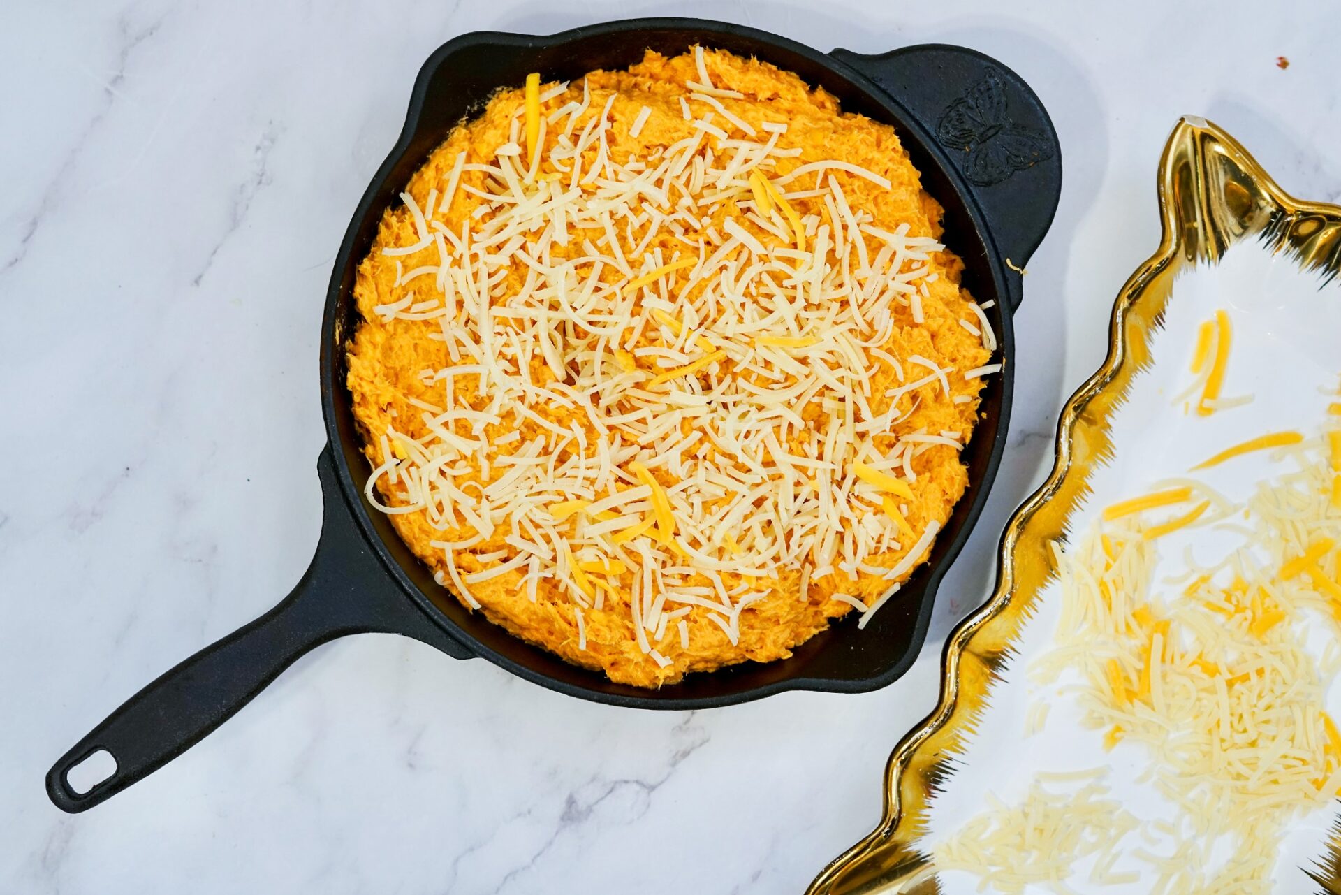 Topping unbaked chicken dip with shredded cheese.