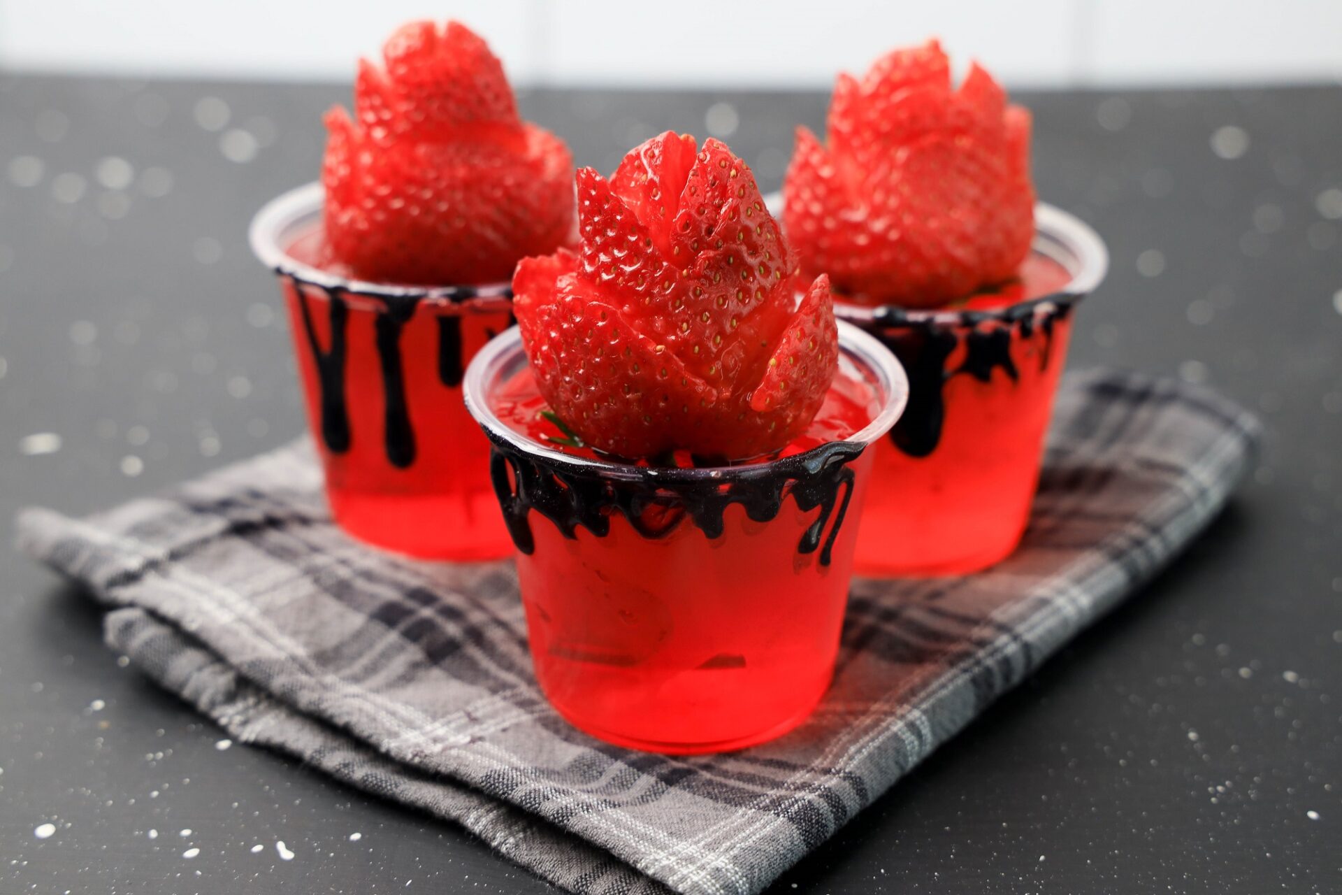 Halloween Rum Jello Shots topped with rose strawberry.