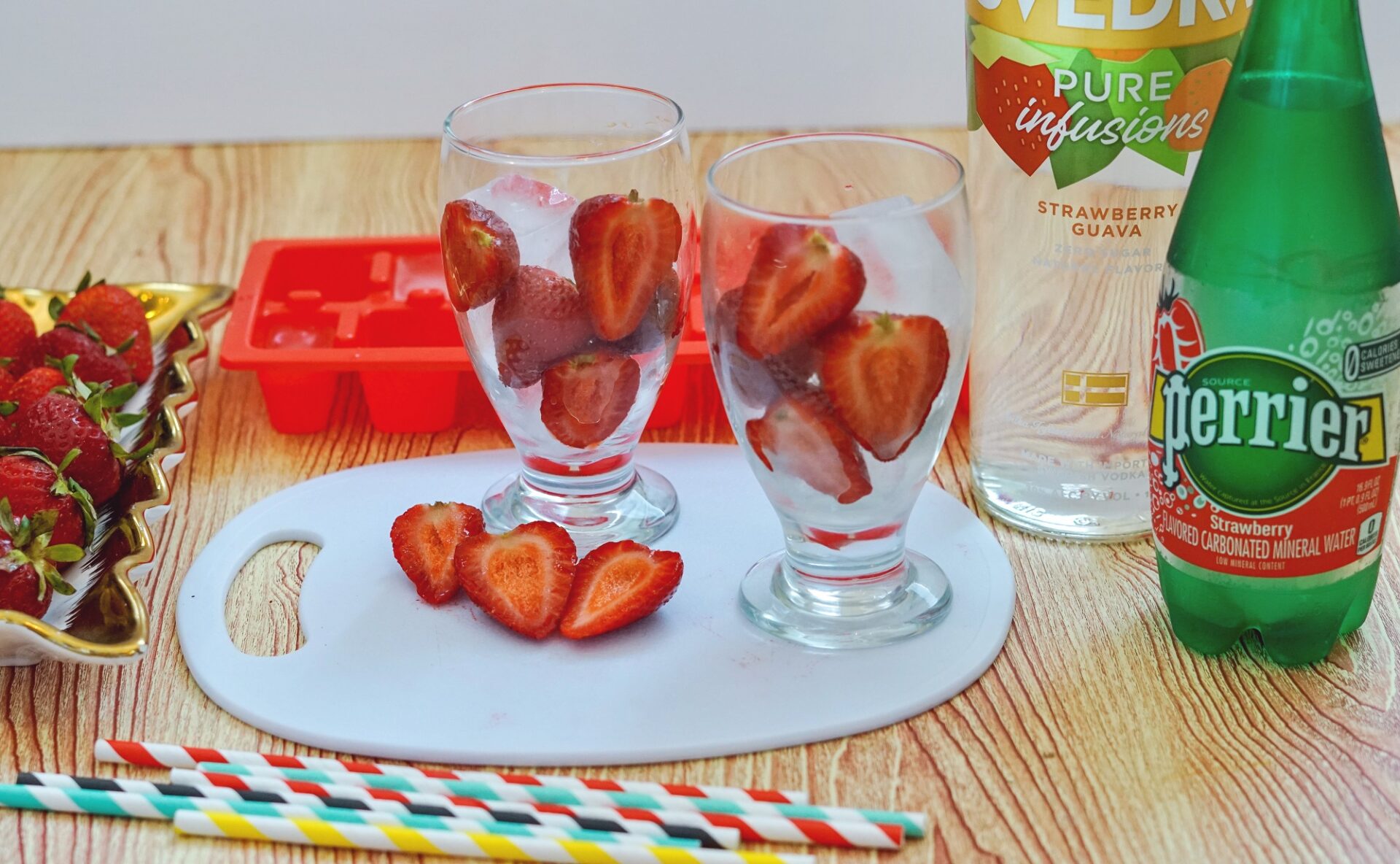 Adding sliced strawberries to glasses with ice.