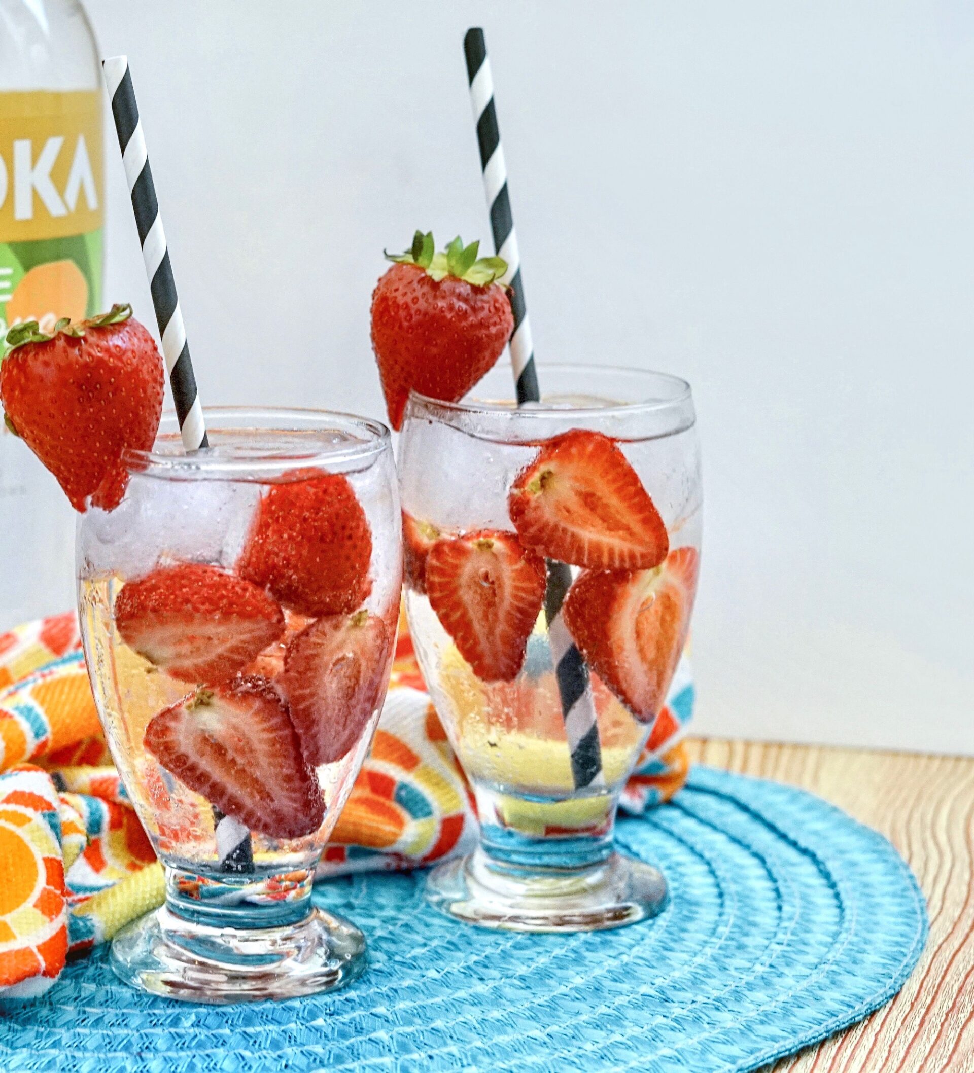 2 glasses of strawberry seltzer on a table with ingredients.