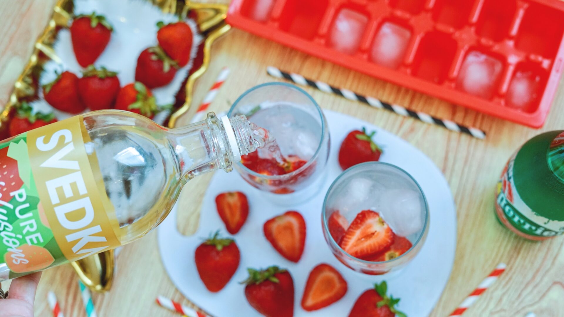 Pouring vodka into a glass of strawberries and ice.