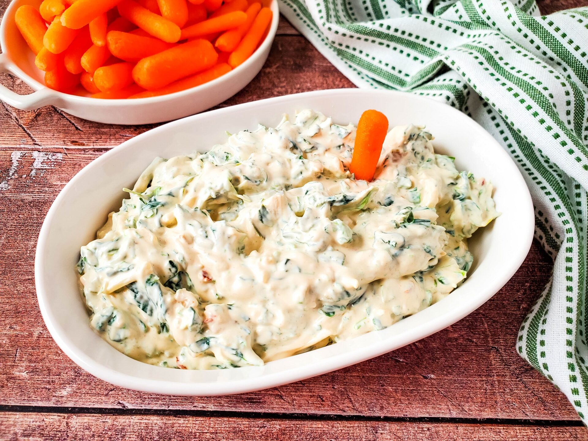 Knorr spinach dip recipe in a baking dish with a baby carrot sticking out of it.