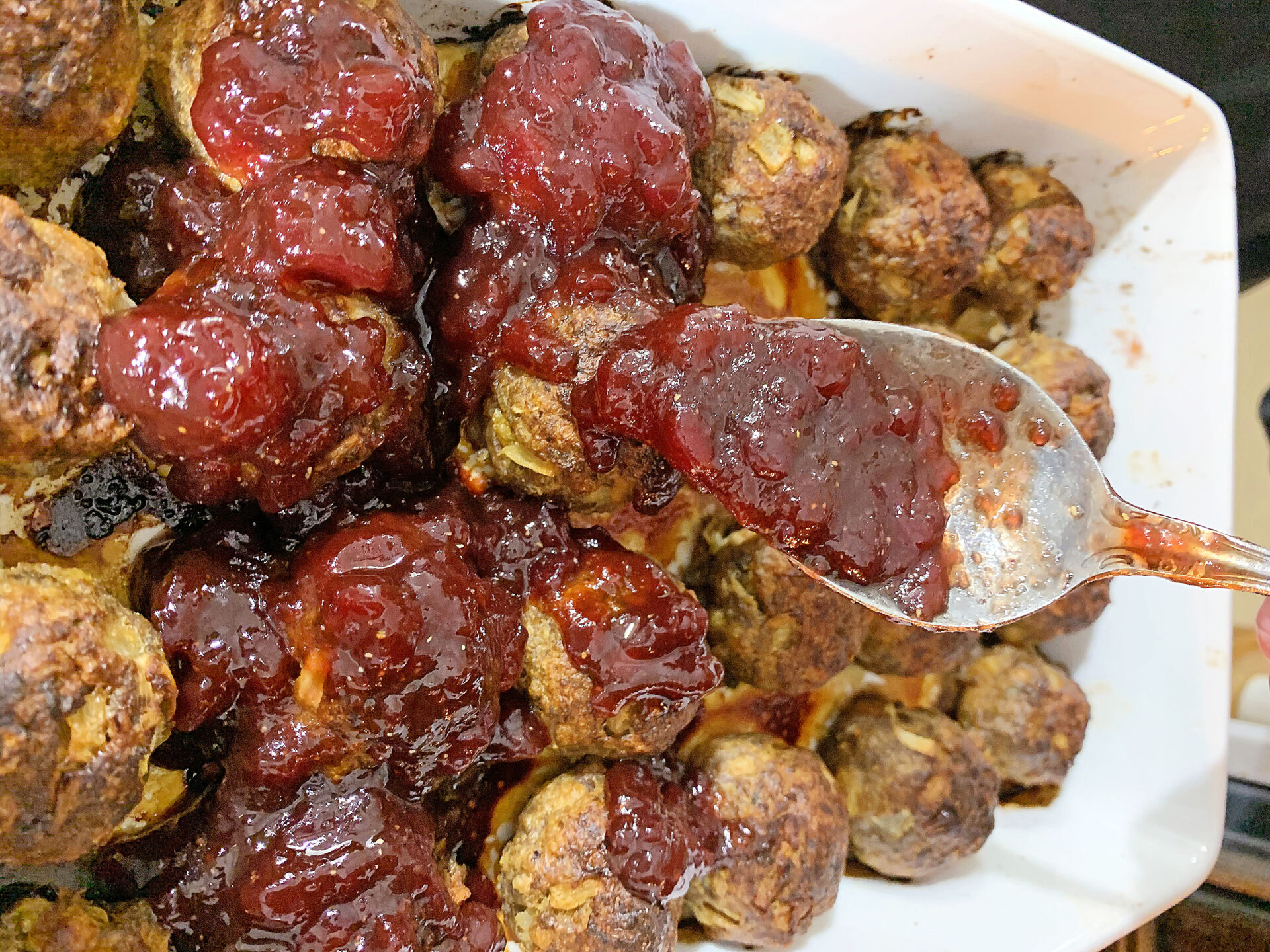 Adding BBQ sauce to cooking meatballs.