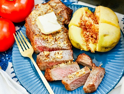 Air Fryer New York Strip steak on a blue plate, along with baked potato