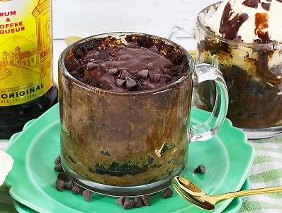 Chocolate chip mug cake with Kahlua and sprinkled cocoa and chocolate chips on top, sitting on a green plate.
