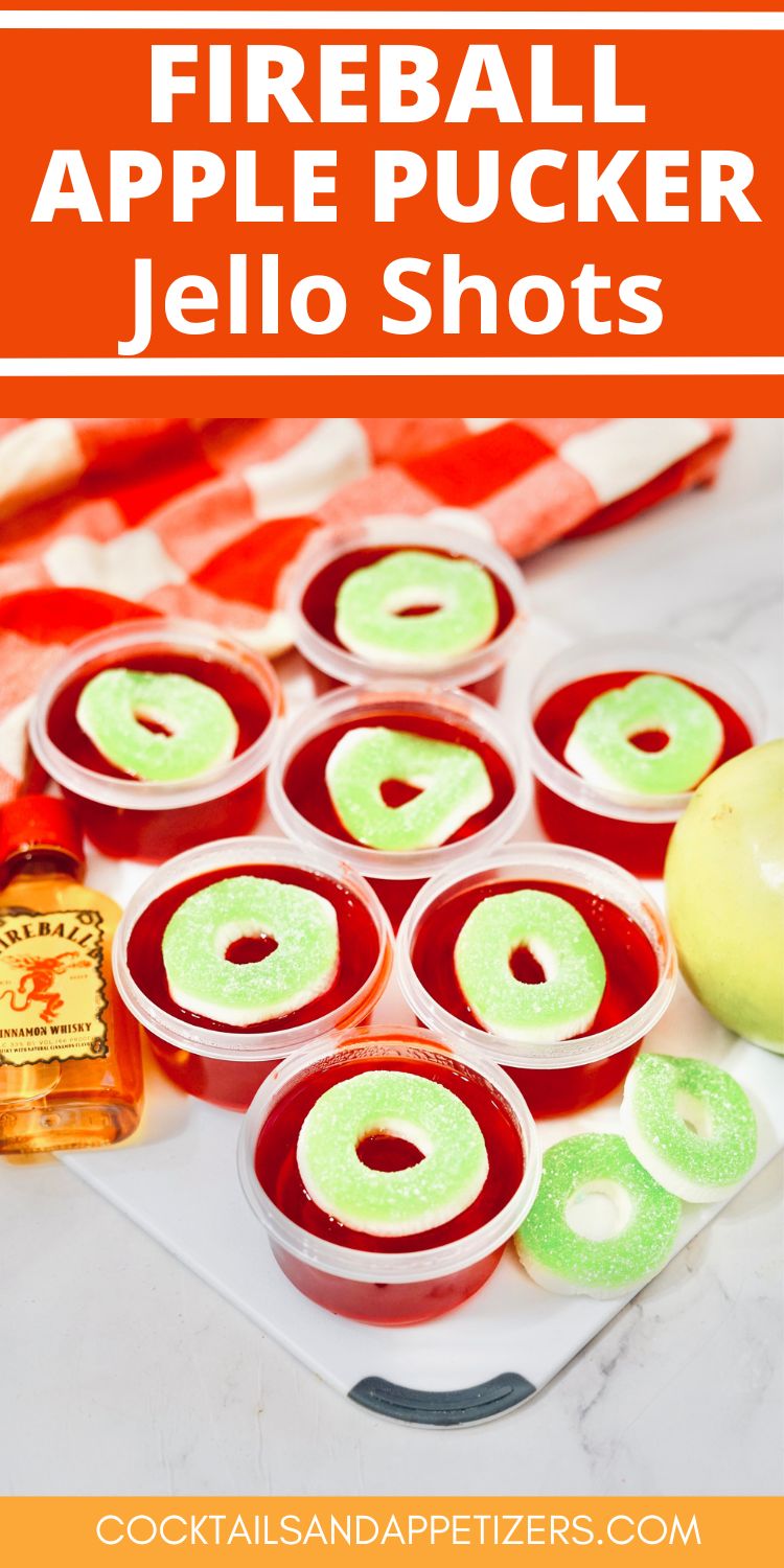 Fireball Apple Pucker jello shots with candy garnish sitting on a tray with a small bottle of Fireball.