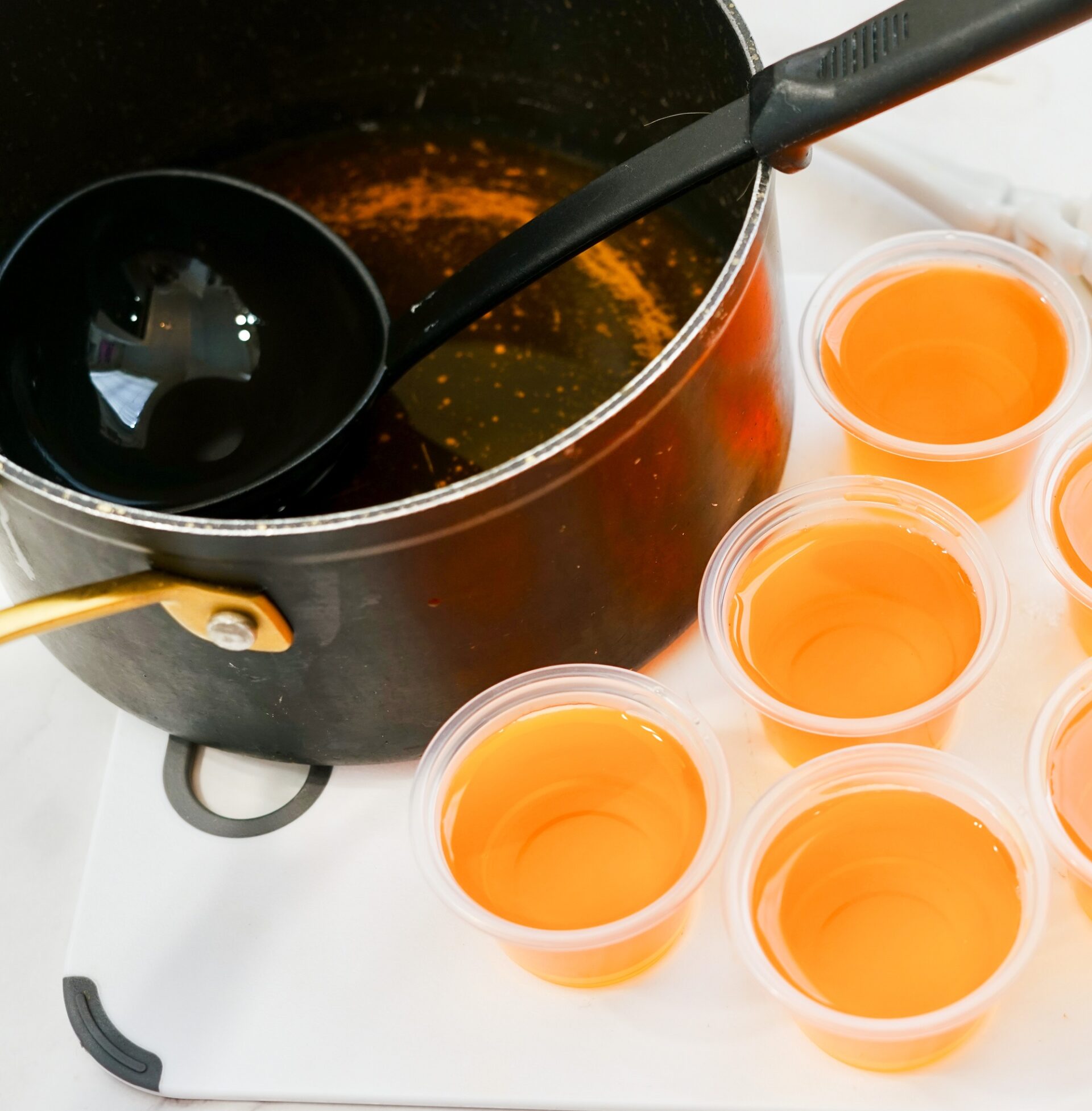 Using a ladle to spoon mixture into condiment cups.