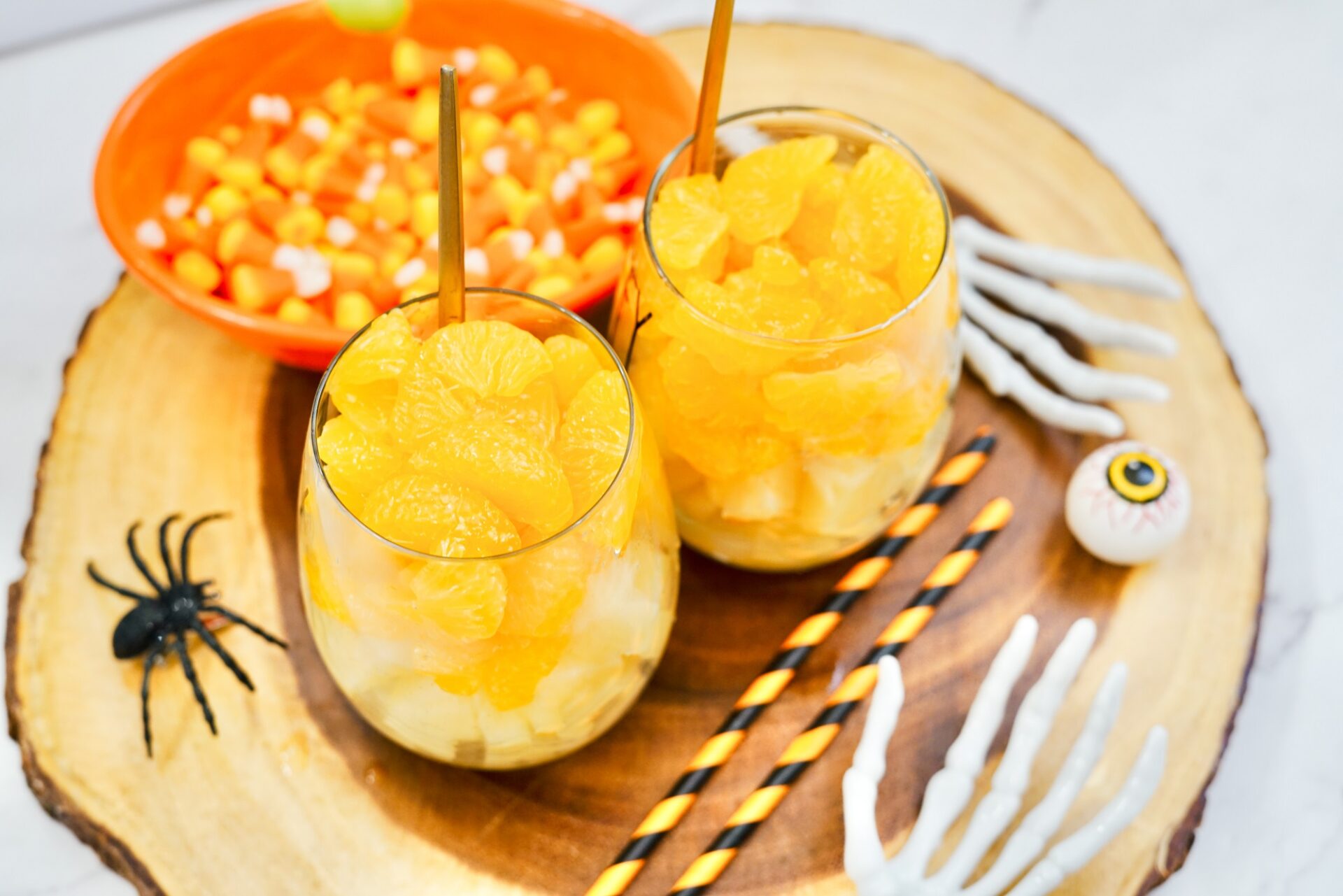 Adding orange slices to glasses with pineapple chunks.