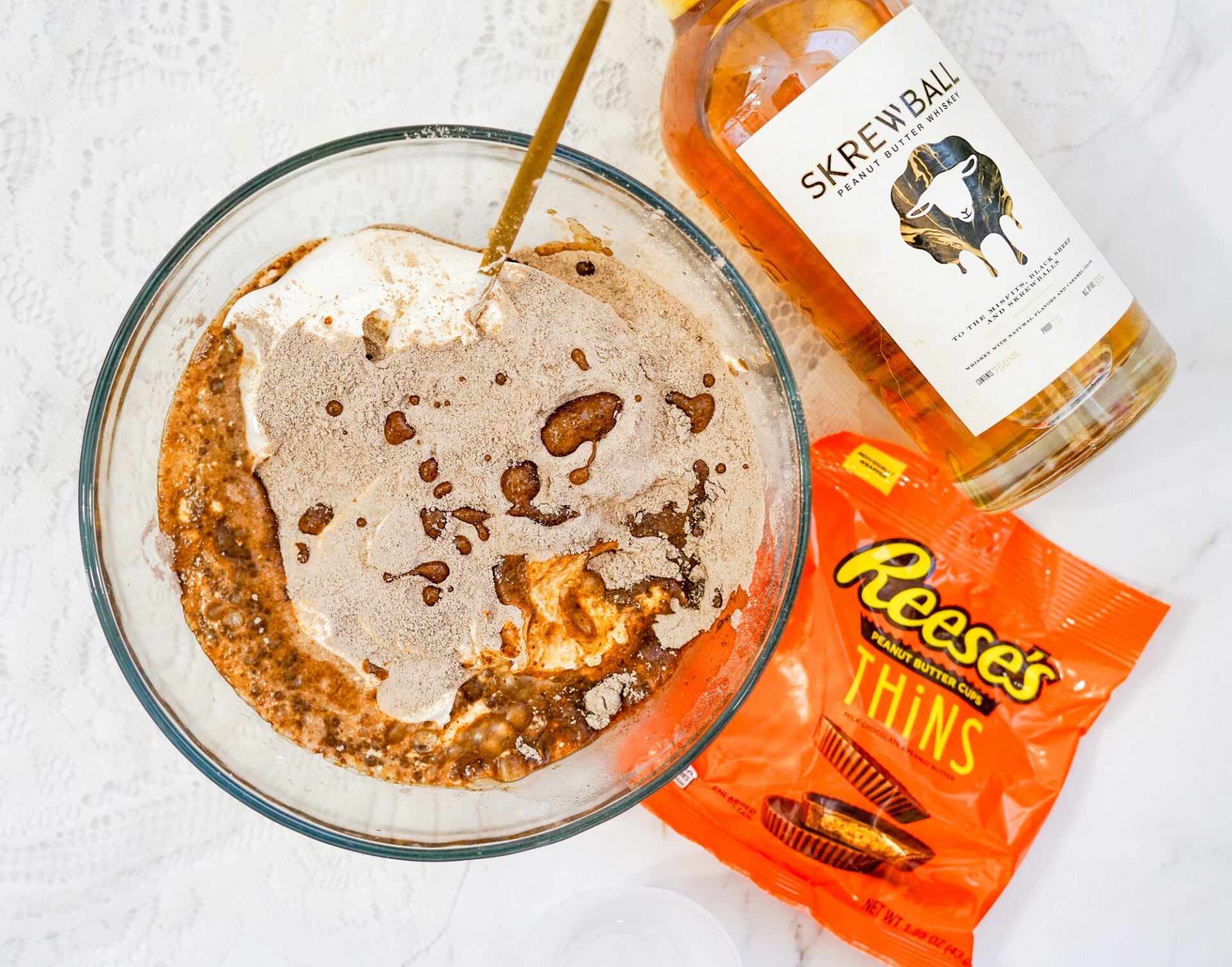 Mixing together whiskey, pudding mix, and whipped topping in a glass bowl.