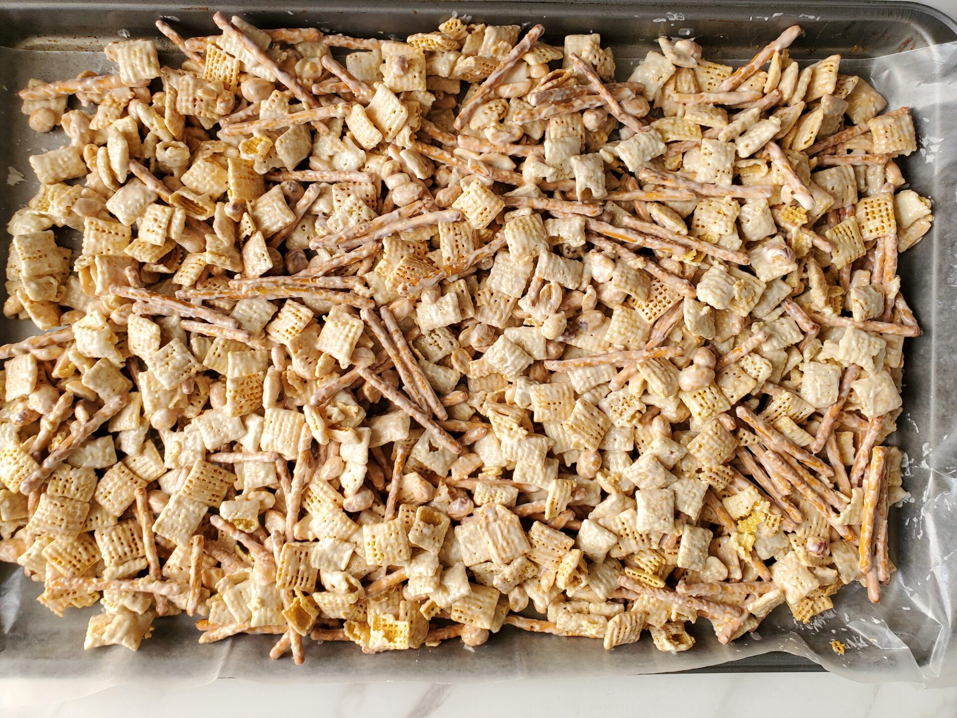 Chex mix on a wax paper lined baking sheet.